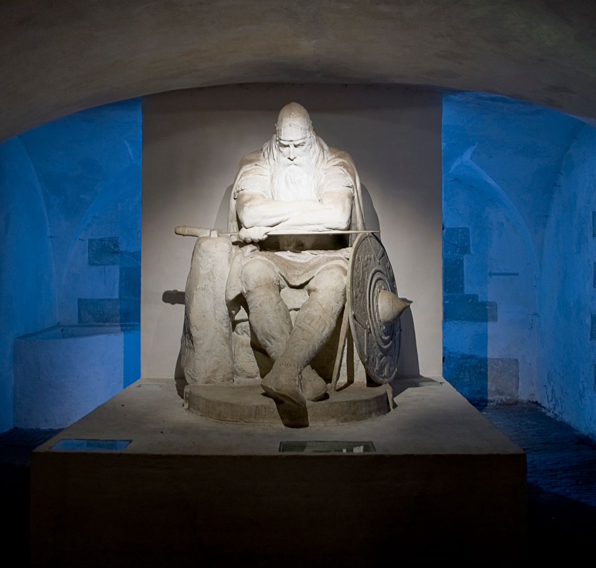 The sculpture of Holger Danske in Kronborg's vaulted casemates, dramatically lit in blue light