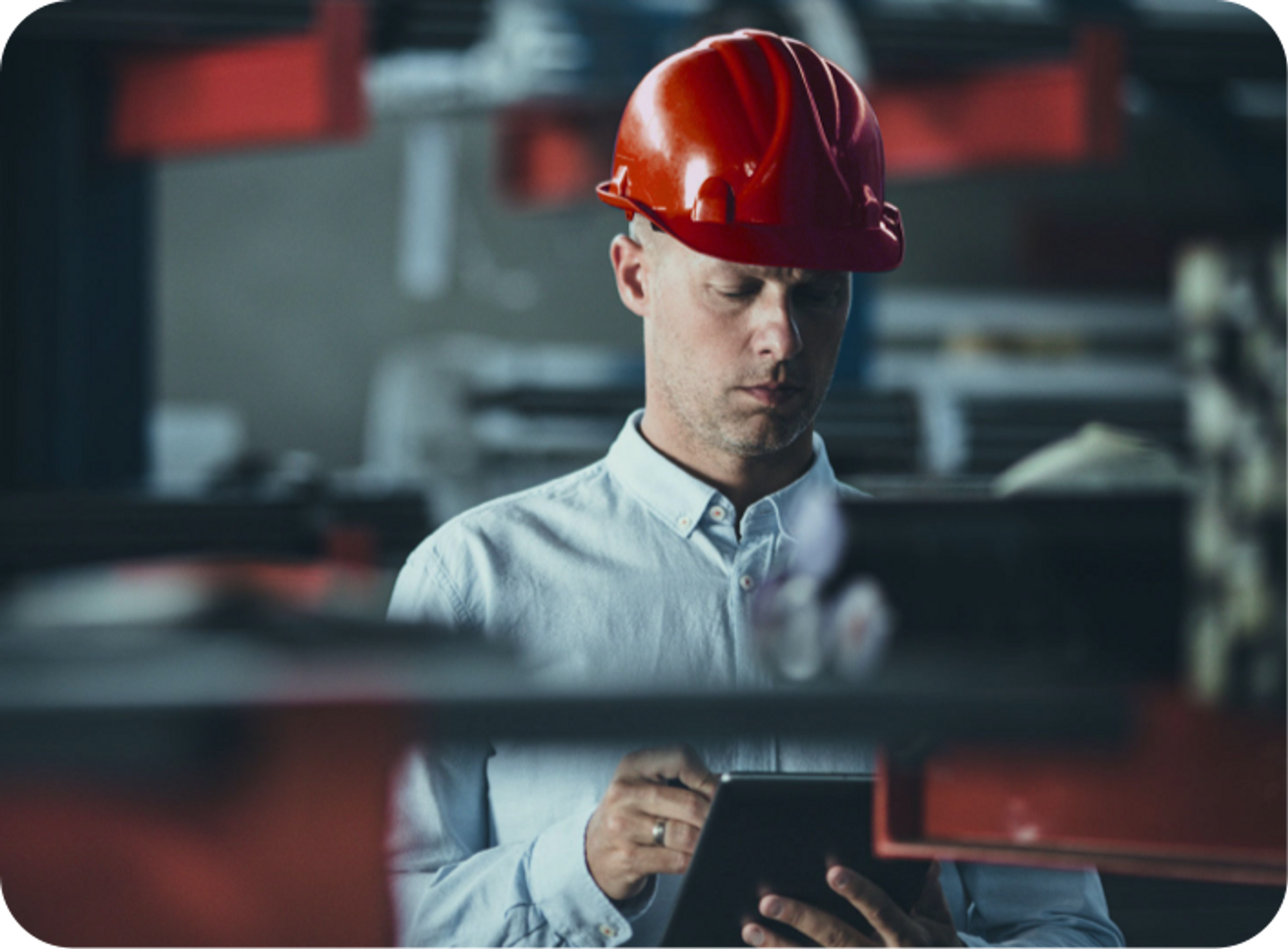 Picture of Caucasian male wearing red hard hat, bllue collared shirt and wearing silver wedding ring , operating an ipad using a stylus in a warehouse setting