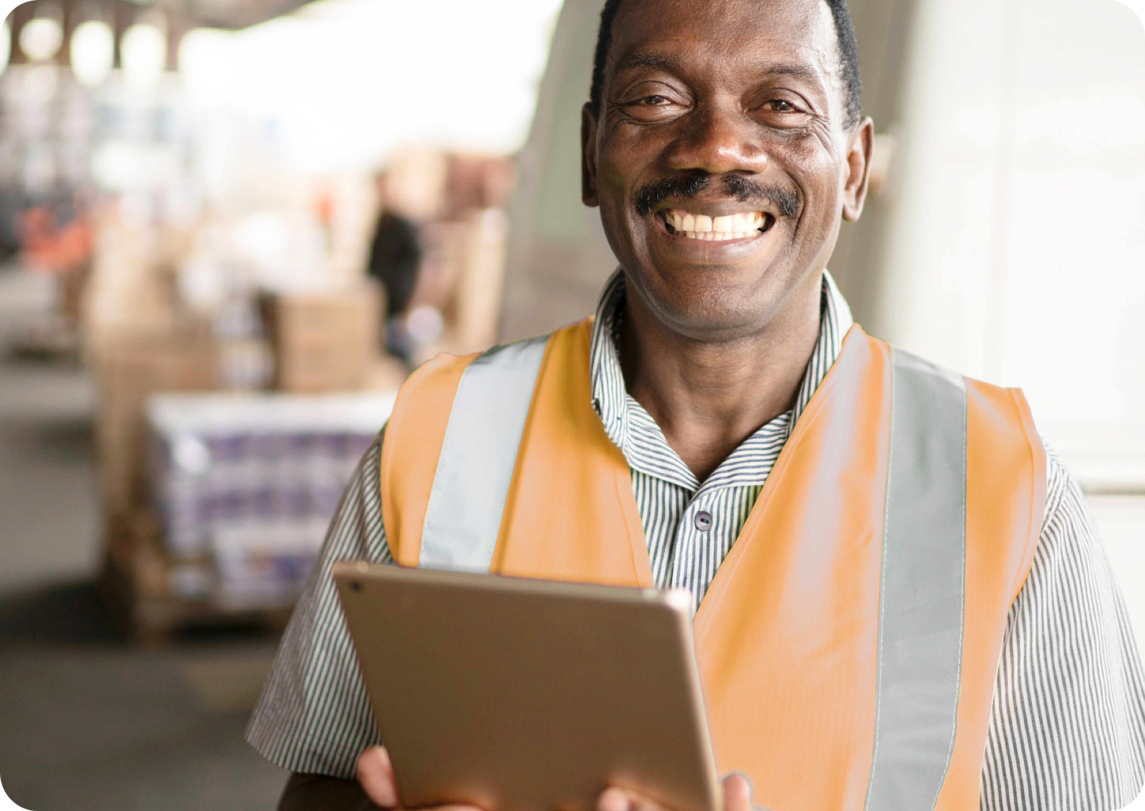 Picture of African man smiling wearing orange safety vest and holding an iPad