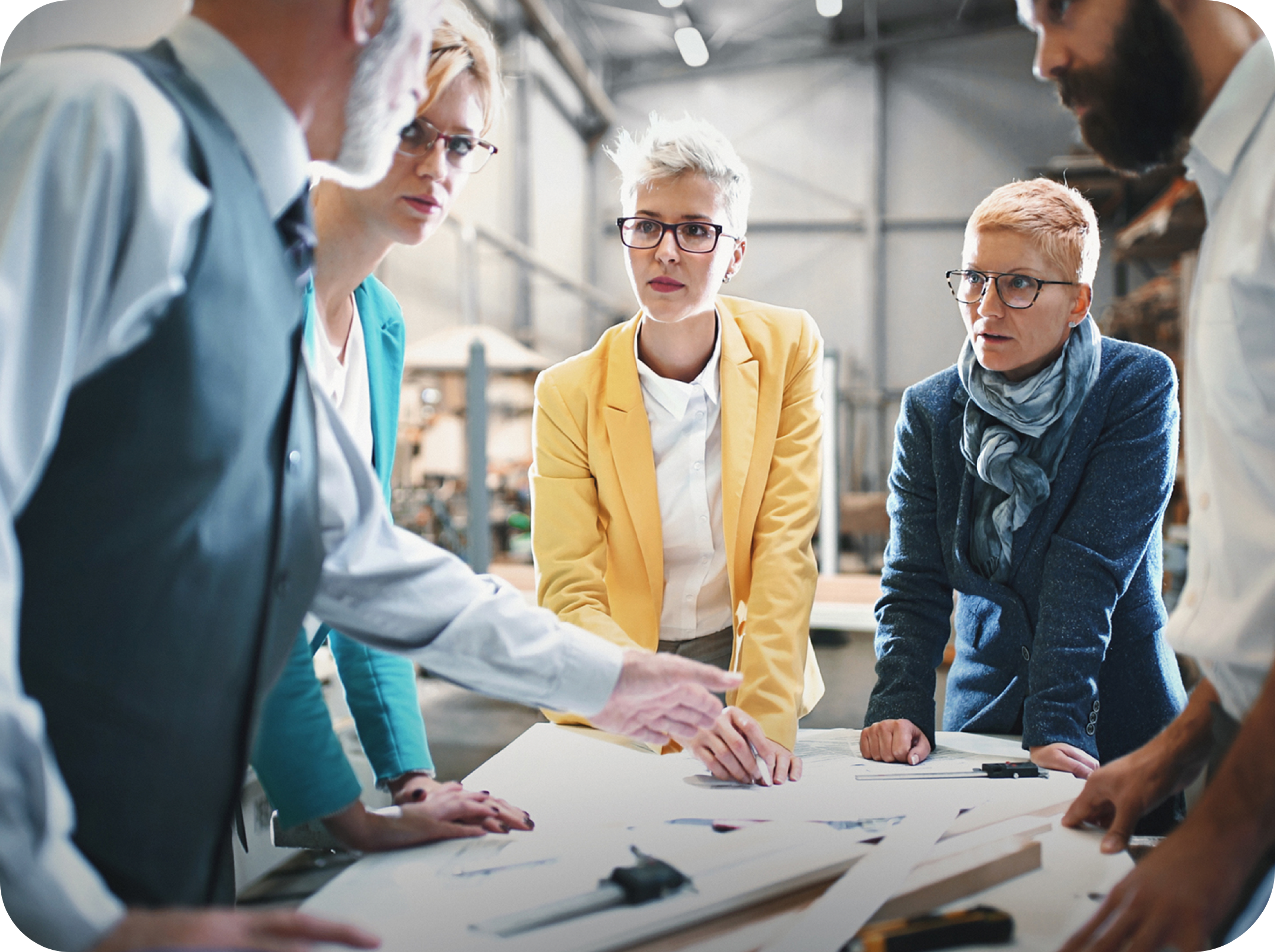 Image of man explaining a concept to three women with short hair and wearing blazers