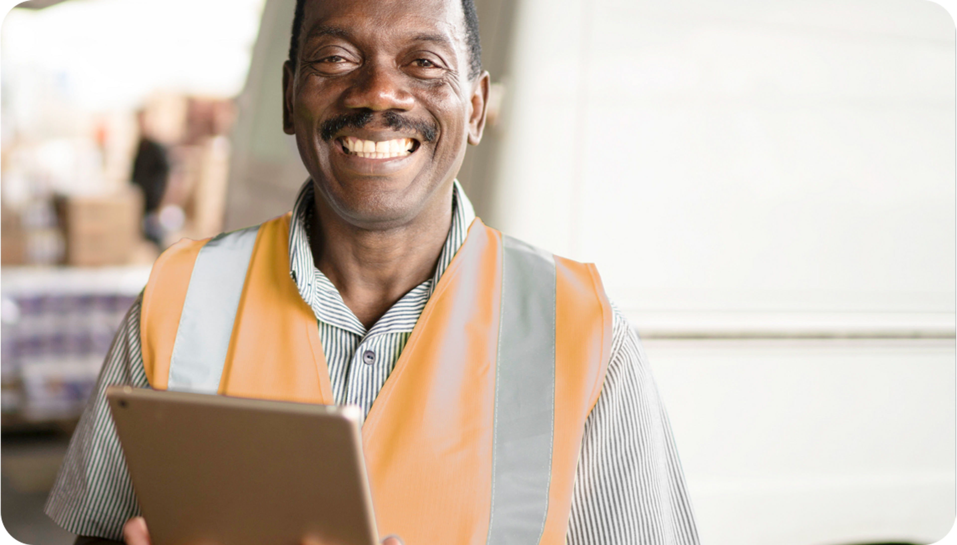 Picture of African man smiling wearing orange safety vest and holding an iPad 