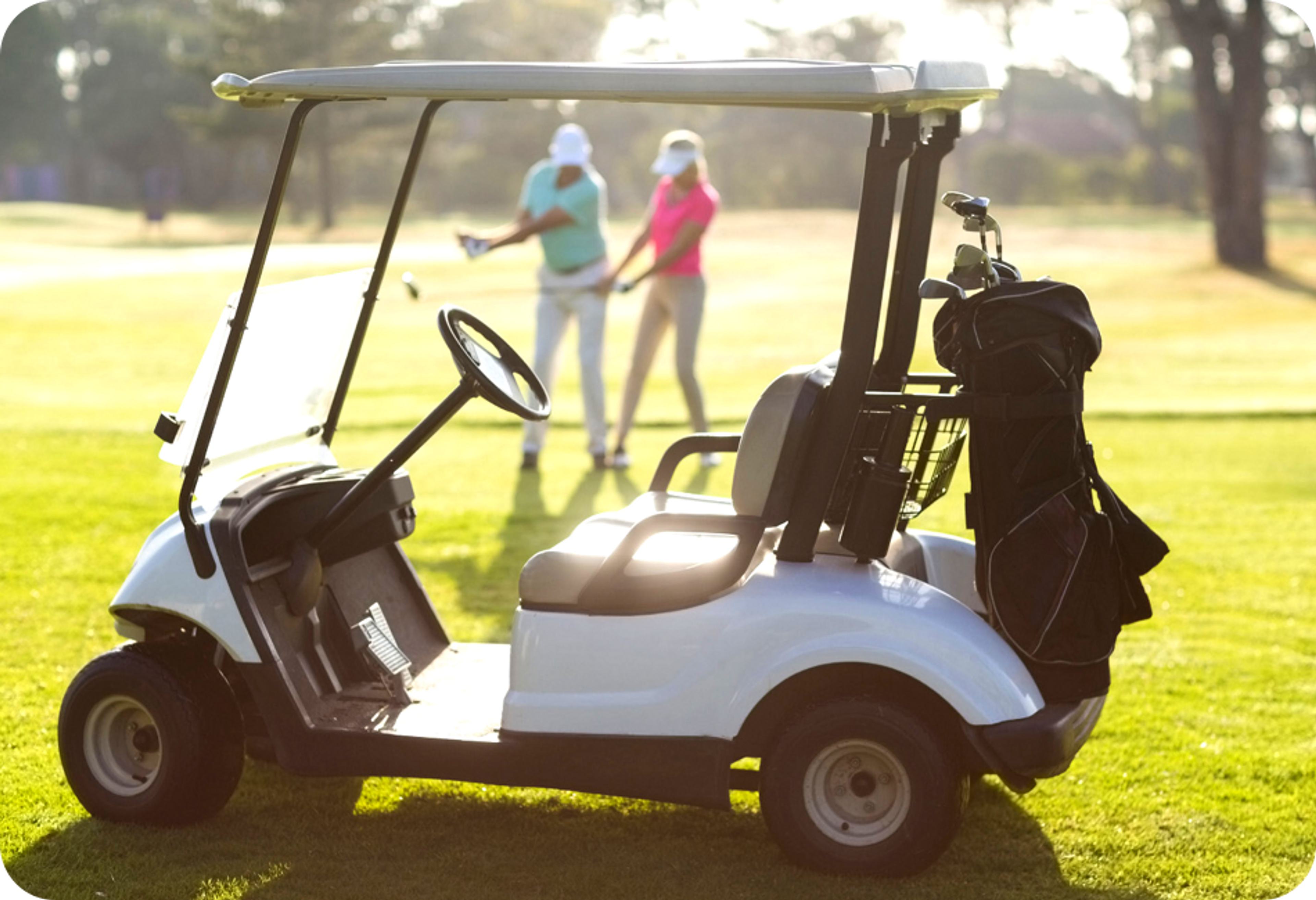 Photo d'une voiturette de golf blanche avec golfeur et golfeuse en arrière-plan