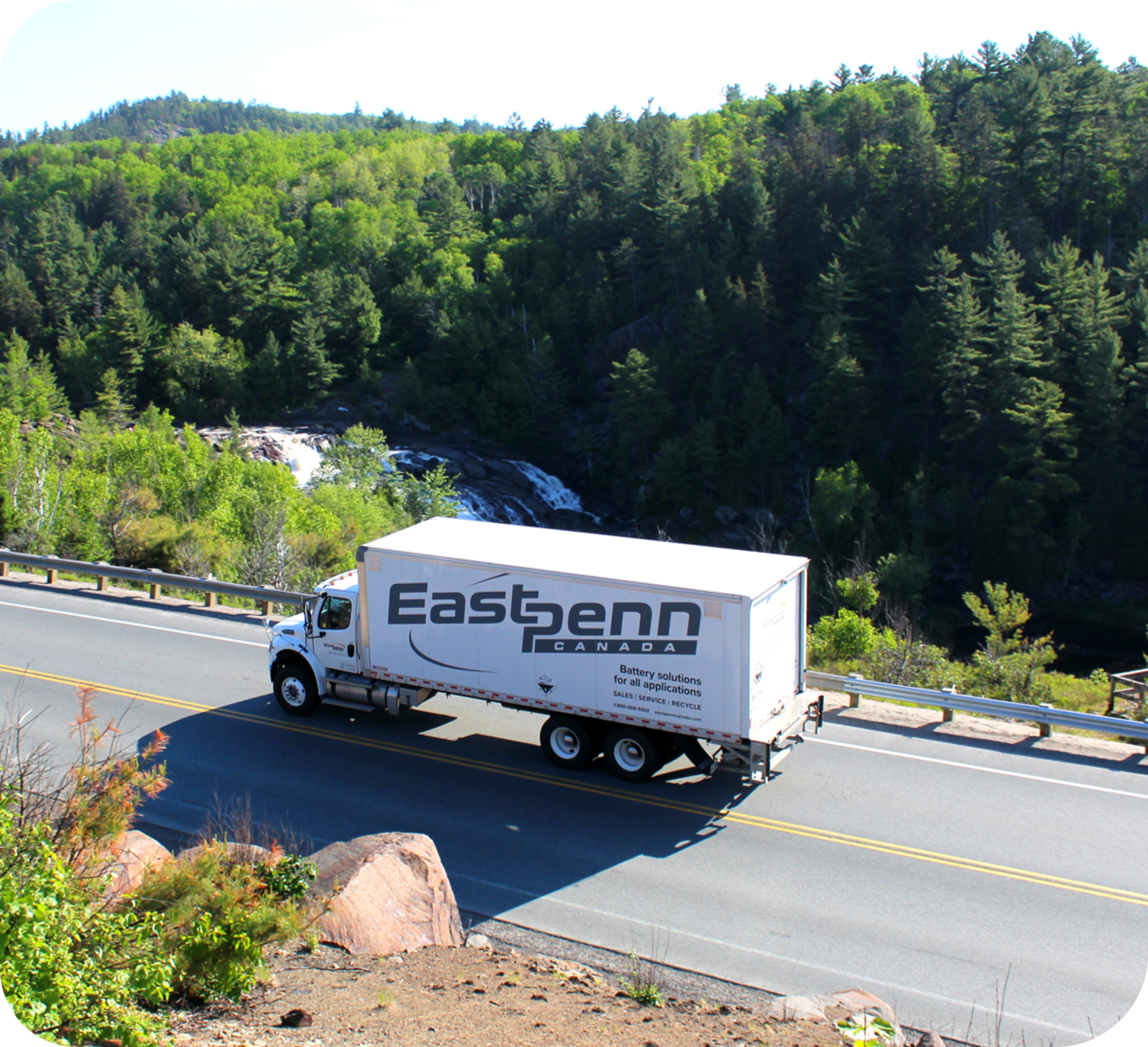Picture of birds eye view of East Penn branded truck on a highway surrounded by trees