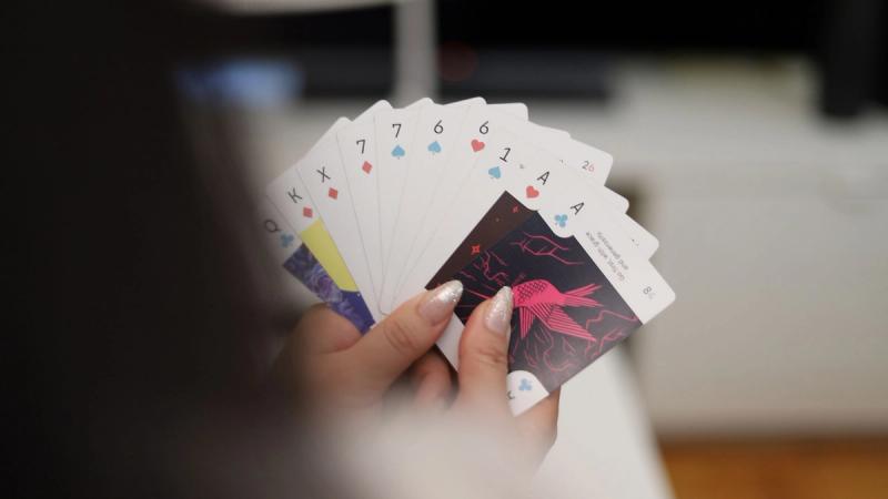 A woman holds up a hand of cards for the Crazy Aces game, with two Aces on the right side.