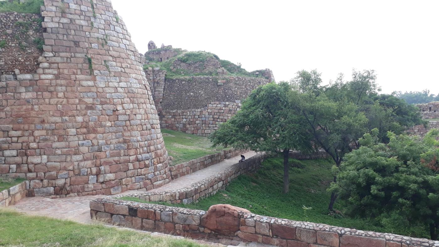 The massive sloping stone ramparts and ruined walls of Tughlaqabad Fort, the fortified capital built by Ghiyath al-Din Tughlaq near Delhi.
