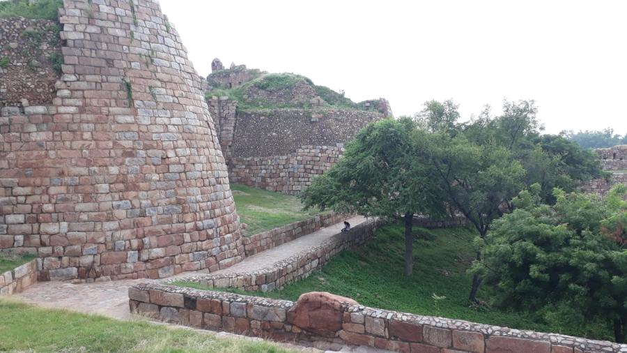 The massive sloping stone ramparts and ruined walls of Tughlaqabad Fort, the fortified capital built by Ghiyath al-Din Tughlaq near Delhi.