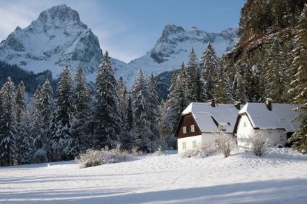 A mountain chalet blanketed in fresh snow beneath jagged alpine peaks
