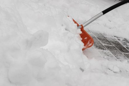 A snow shovel scraping a paved walkway down to bare stone