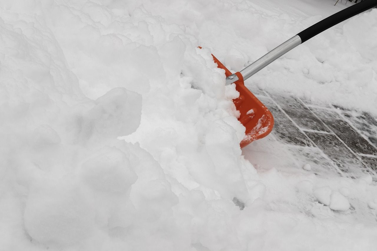 A snow shovel scraping a paved walkway down to bare stone