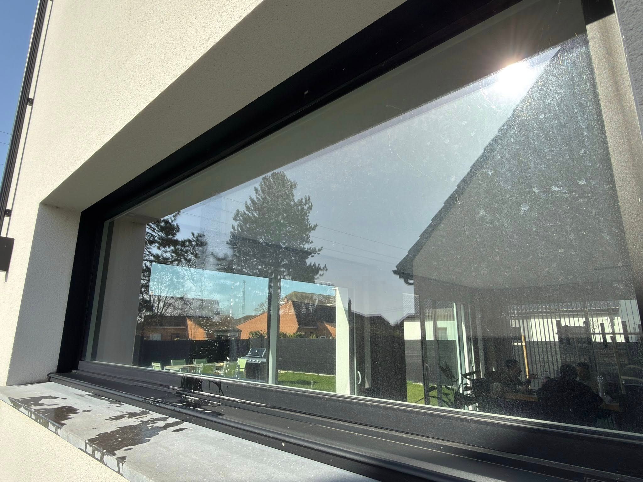 Gros plan sur une vitre sale et marquée par la pollution à Merville avant nettoyage