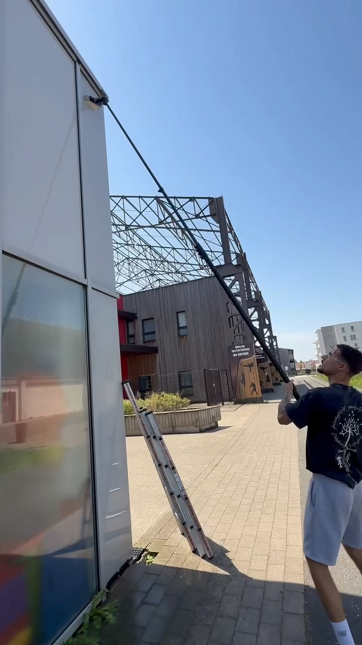 Technicien PAANDAWLV utilisant une grande perche en carbone pour nettoyer la façade d'un bâtiment à Lys-lez-Lannoy.