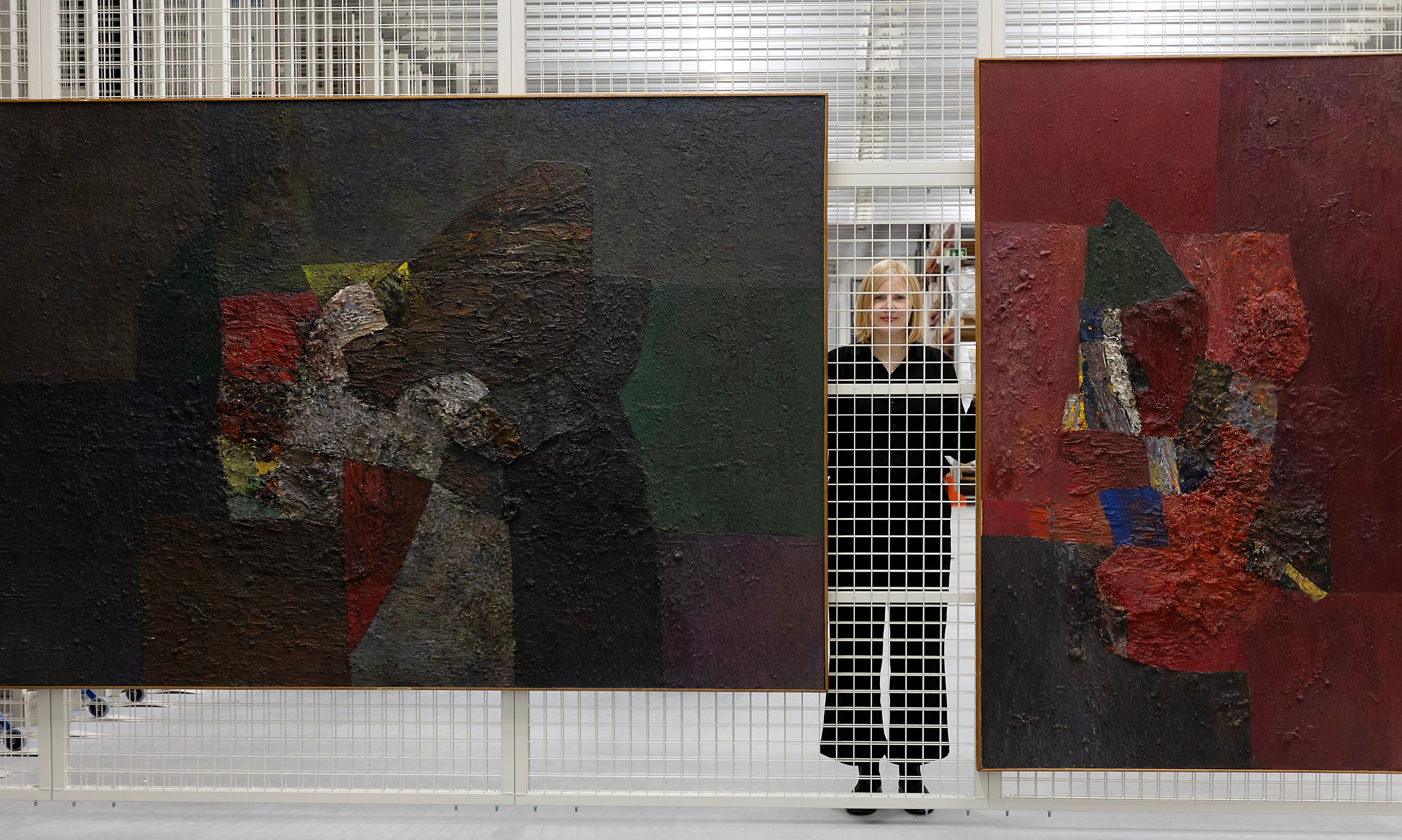 Woman standing behind two art works
