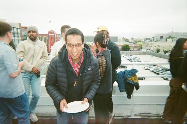 man smiling with a plate at a rooftop social