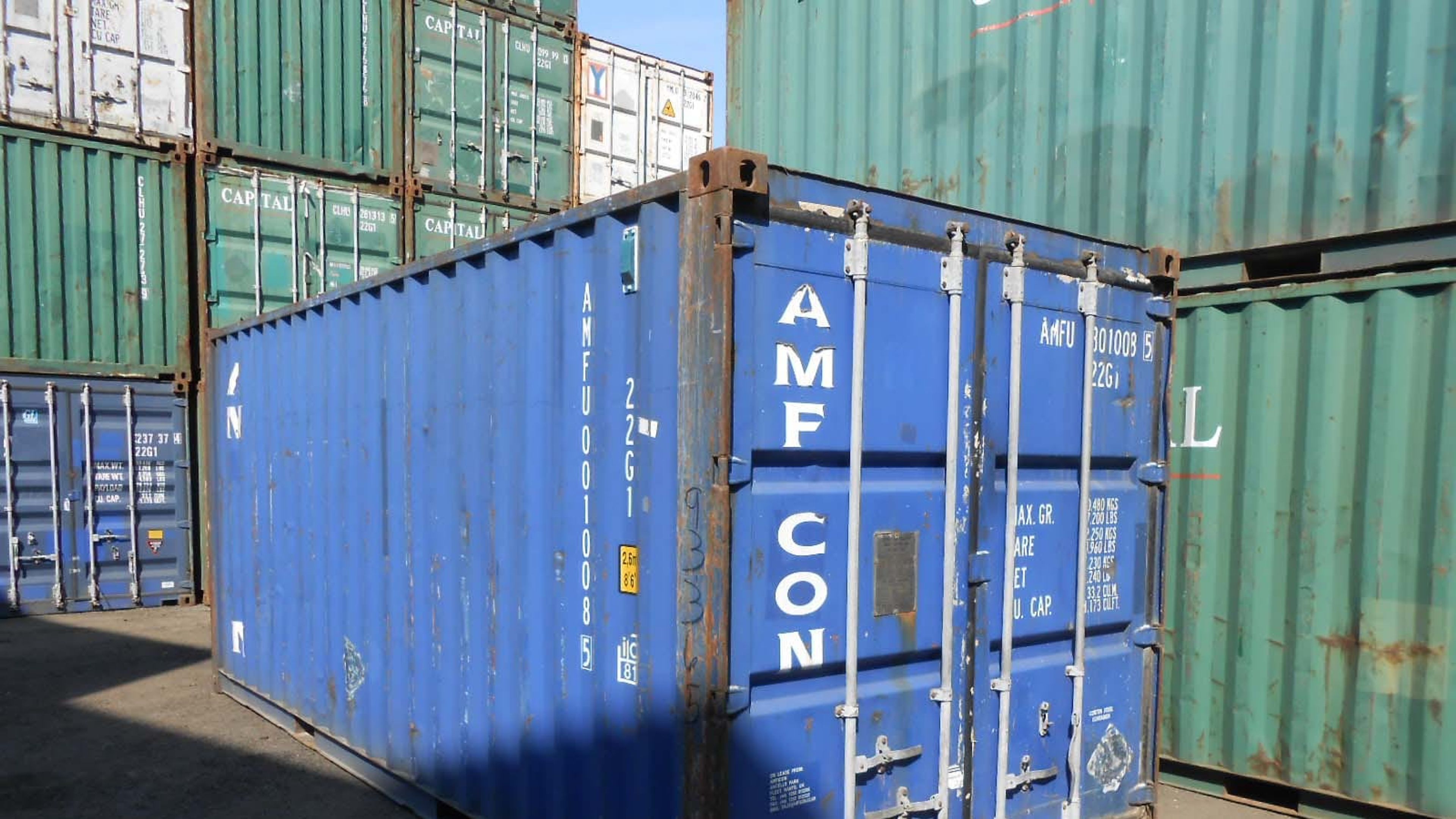 A used 20ft shipping container in a yard with its container number, and CSC safety plate visible on the doors