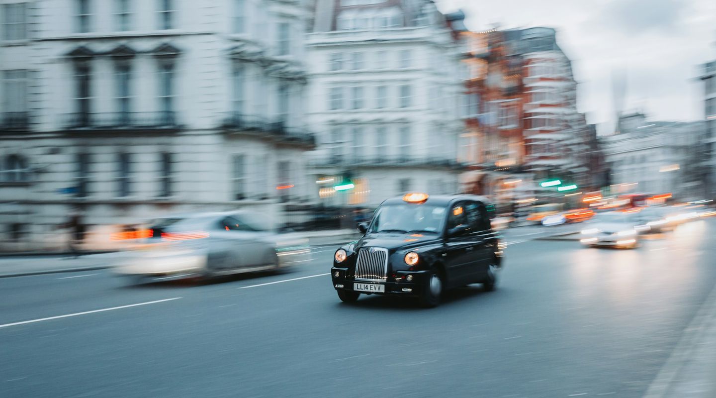 Classic London black cab captured in motion blur on a busy London street at dusk - bus lanes uk