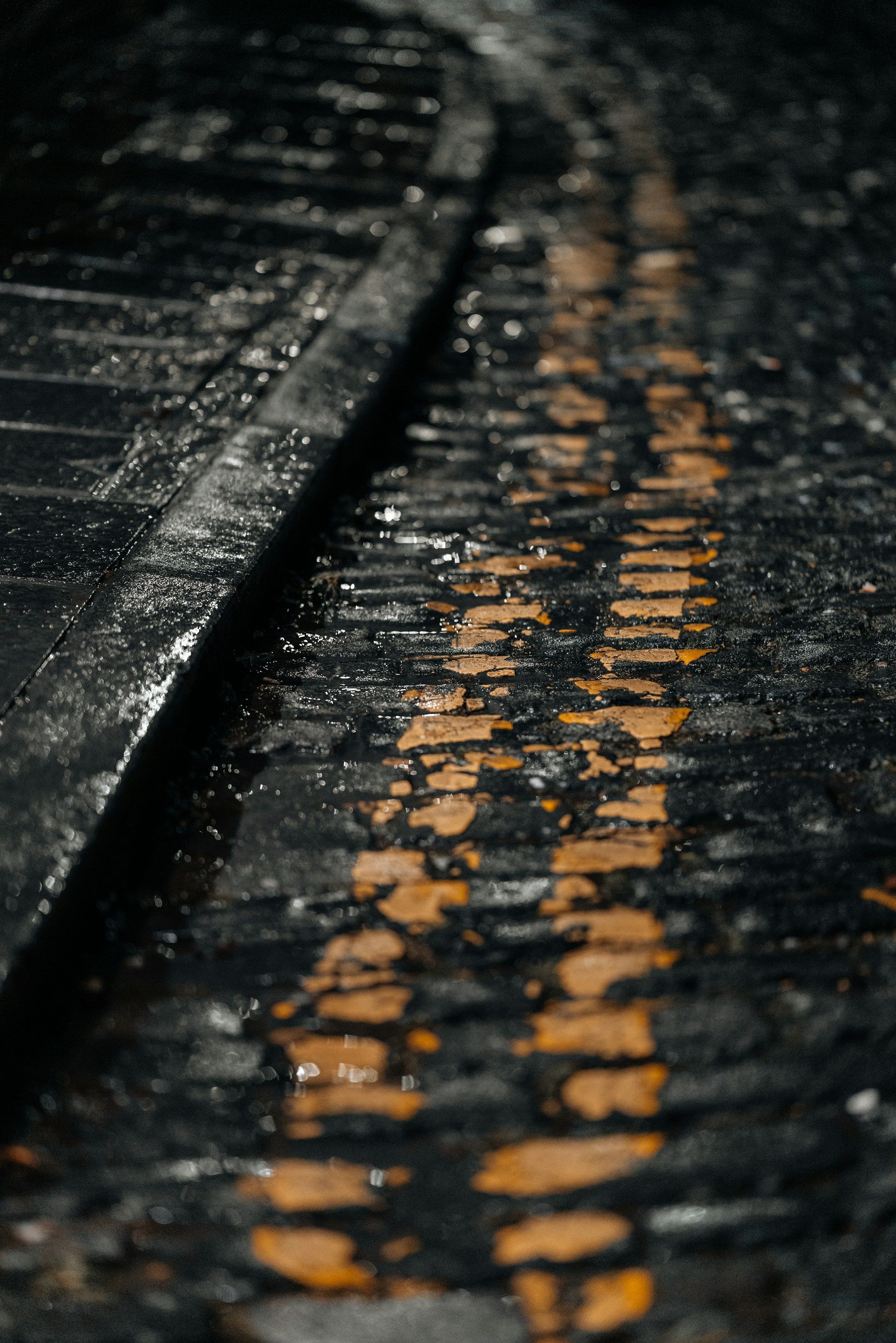 Close-up macro of wet yellow road paint on dark cobblestones at a kerb - parking signs uk