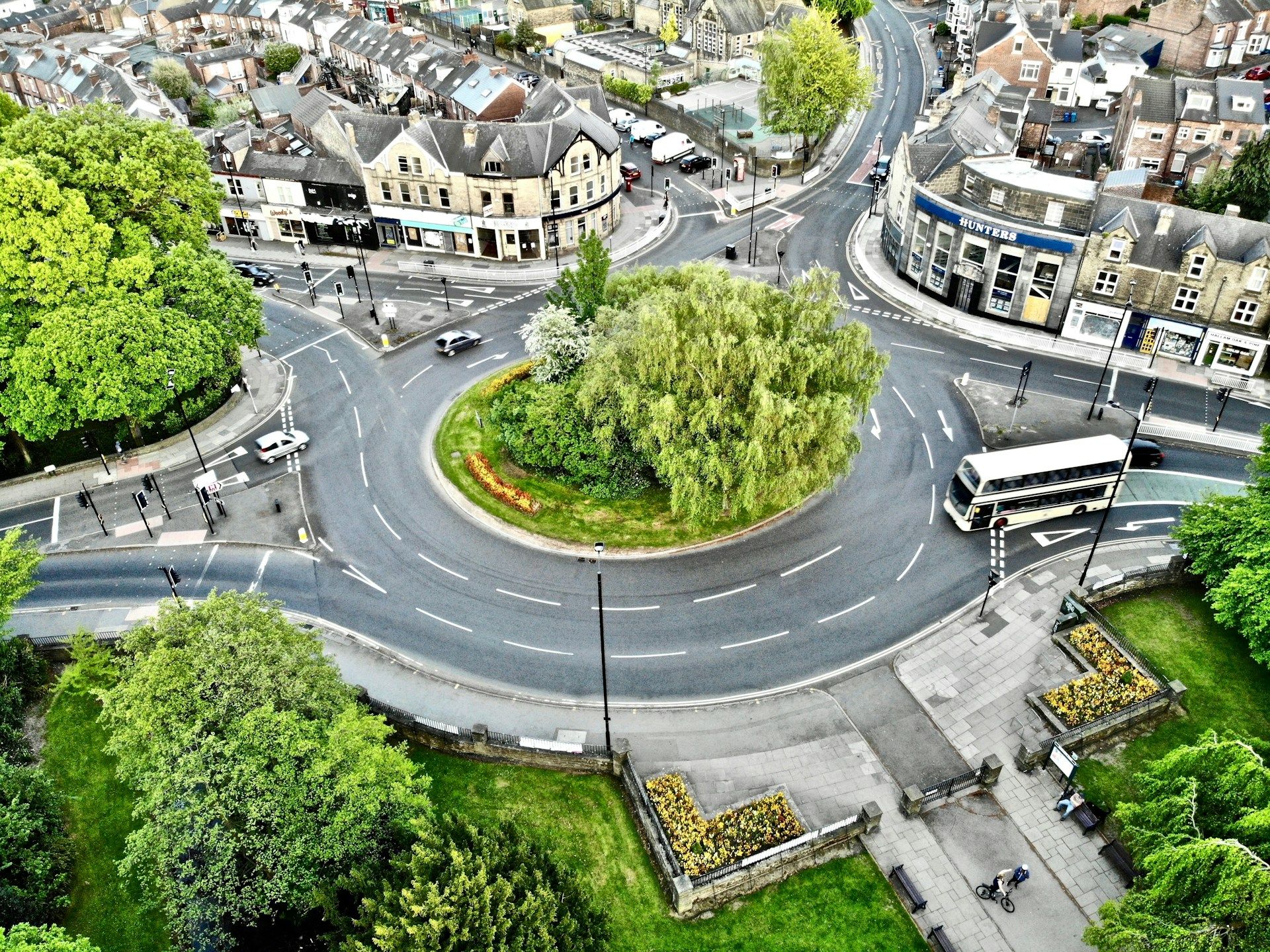 Aerial view of a UK town roundabout with a planted central island containing a willow tree - bus lanes uk