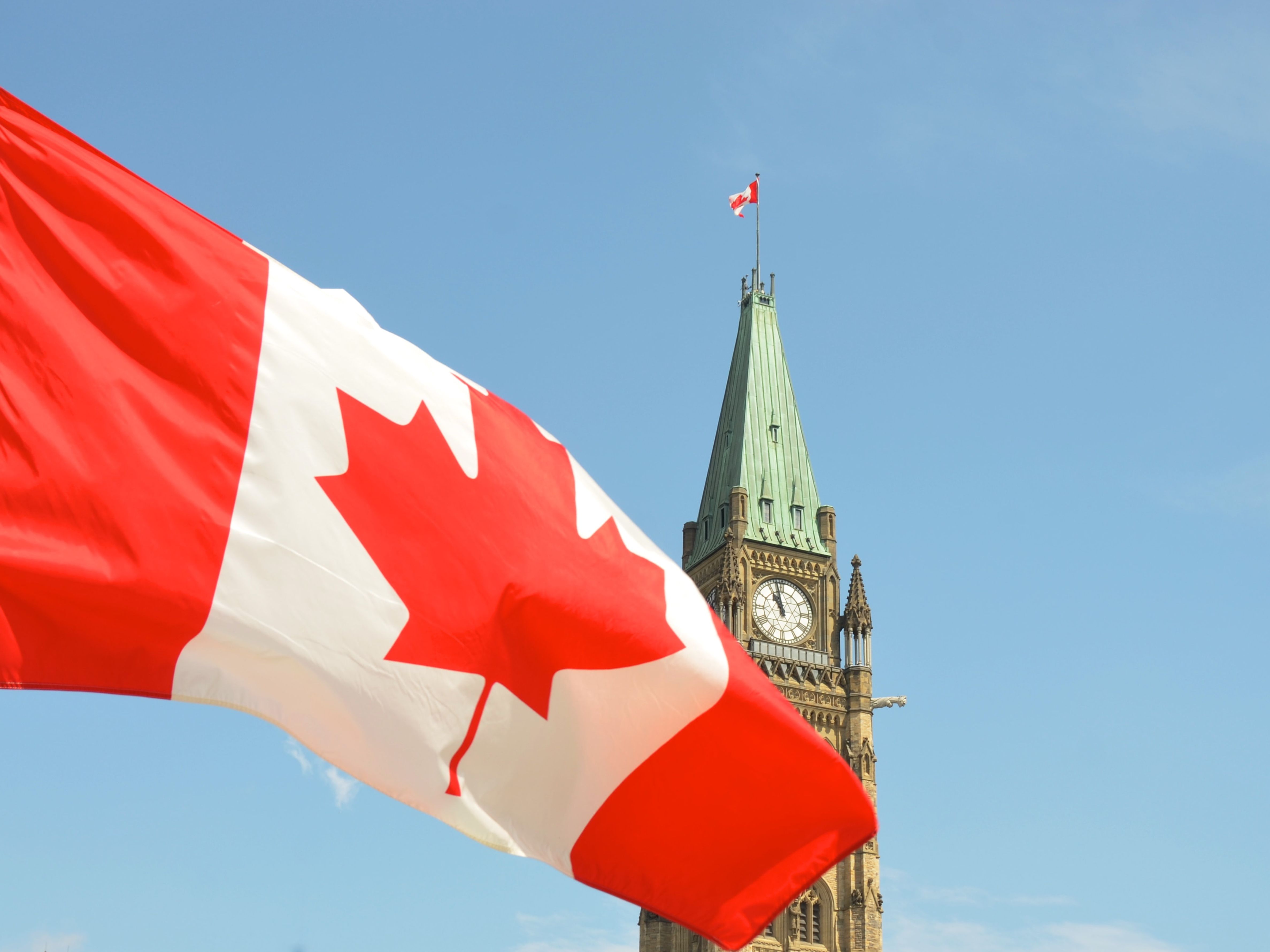 The Canadian flag, with parliament in the background.