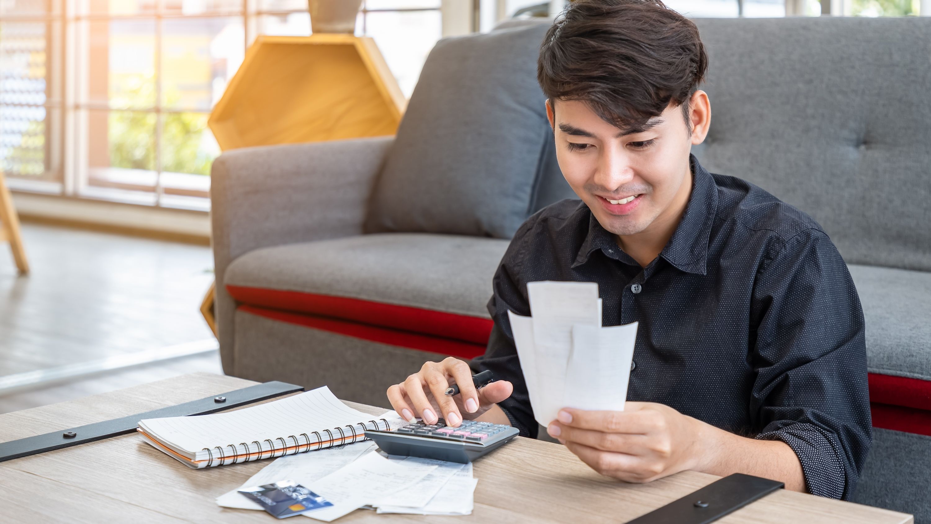 A young person enters values from a receipt into a calculator.