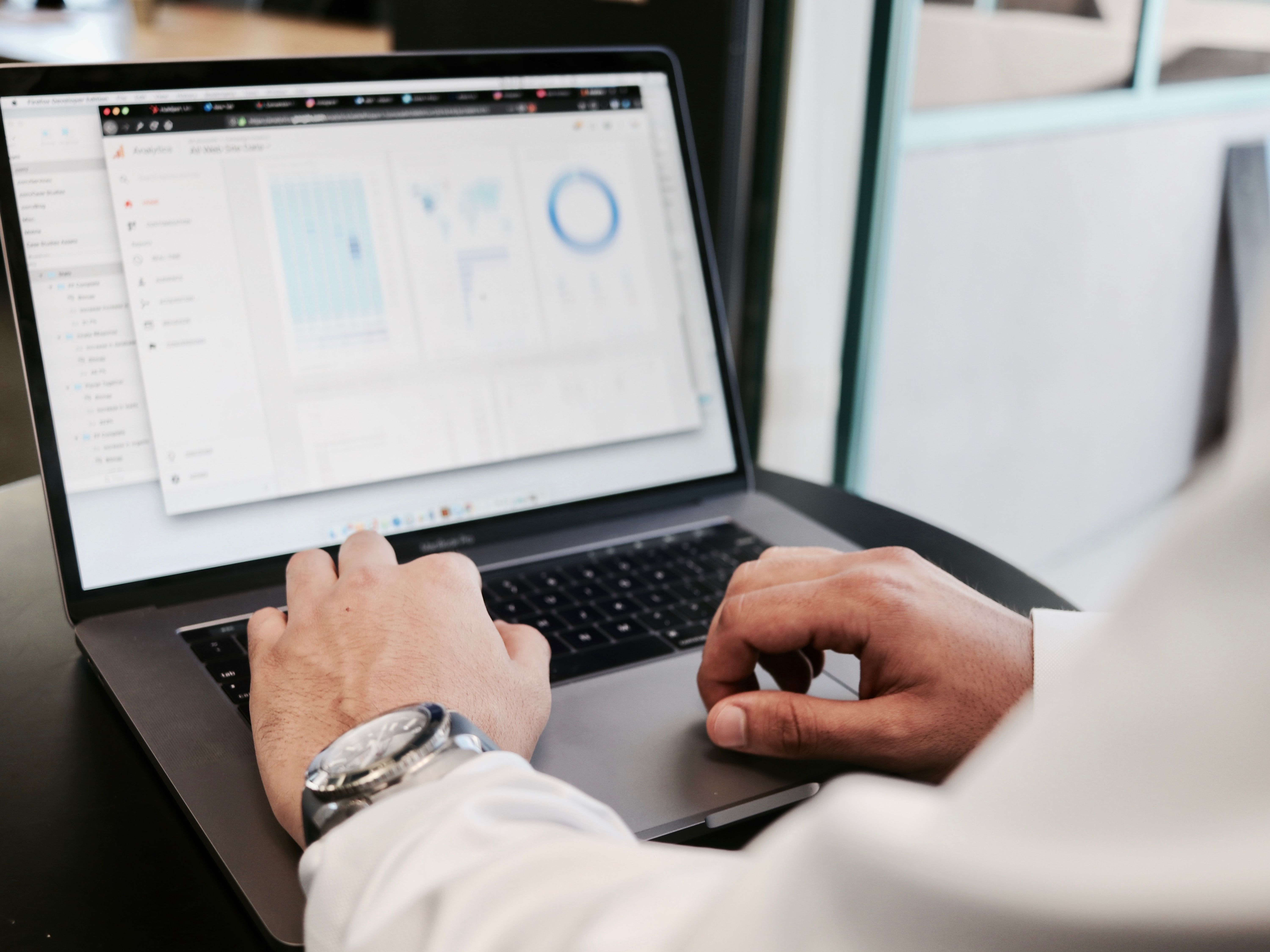 A person in business attire reviews charts on their laptop screen