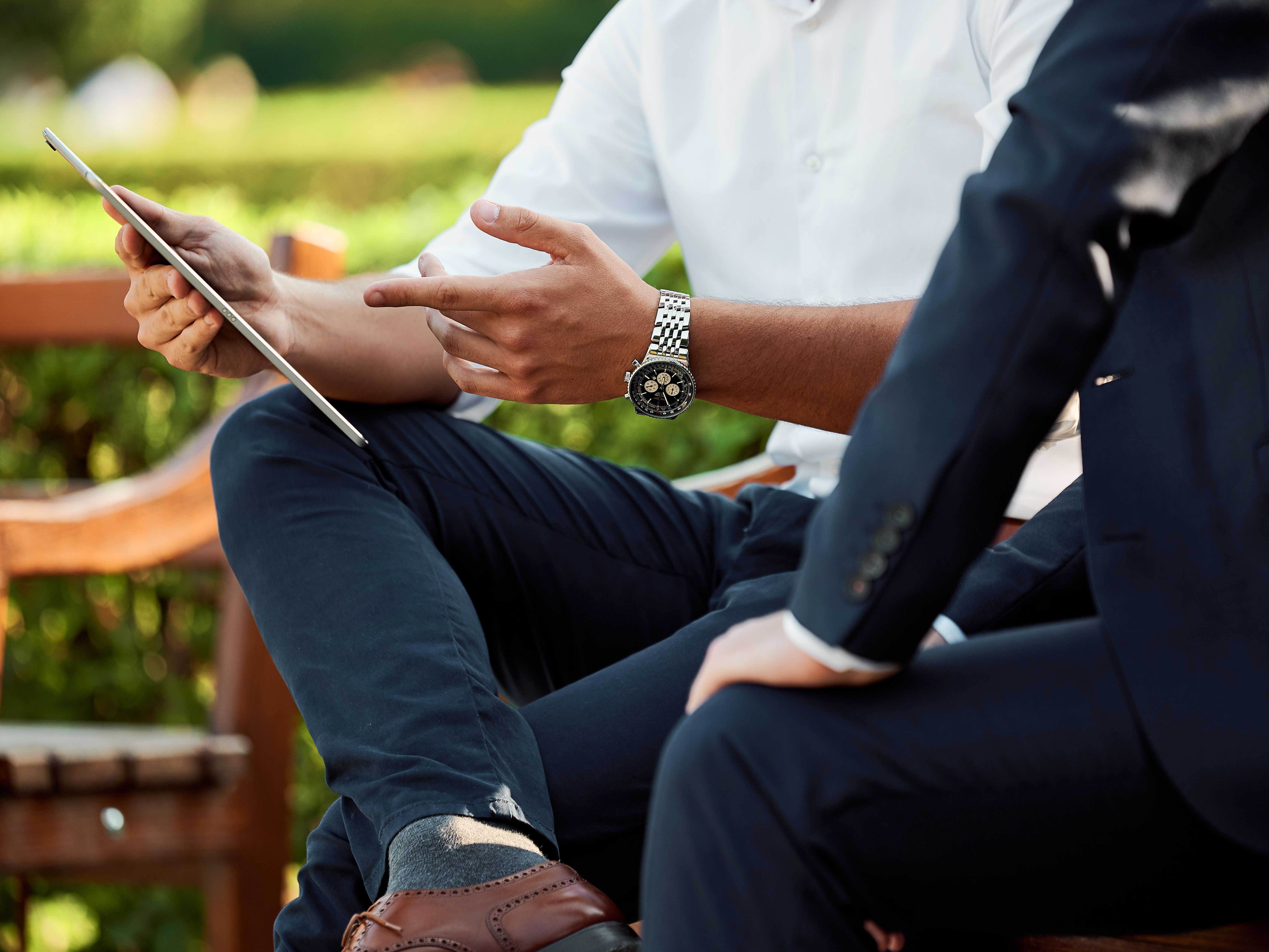 Two business people discuss something appearing on a tablet screen.