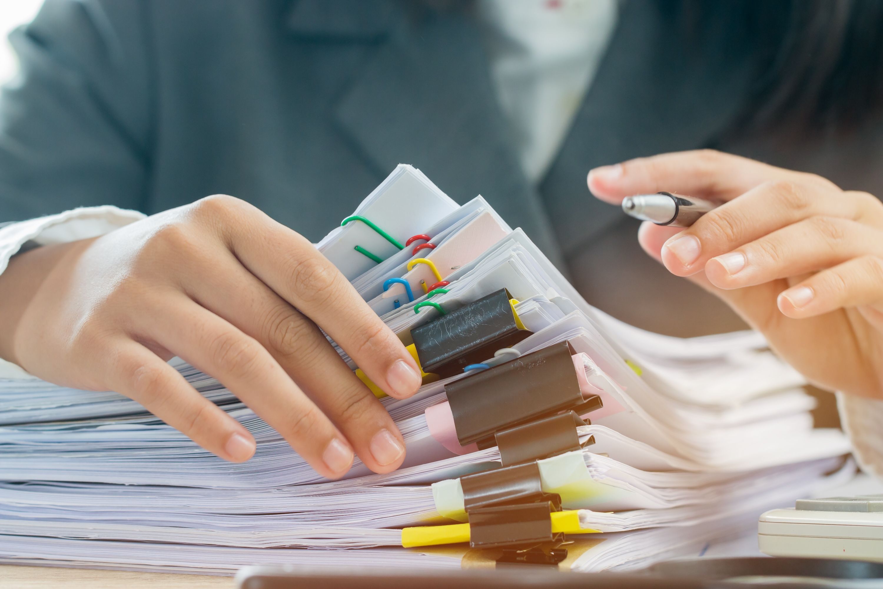 A person flips through a large pile of tax documents.