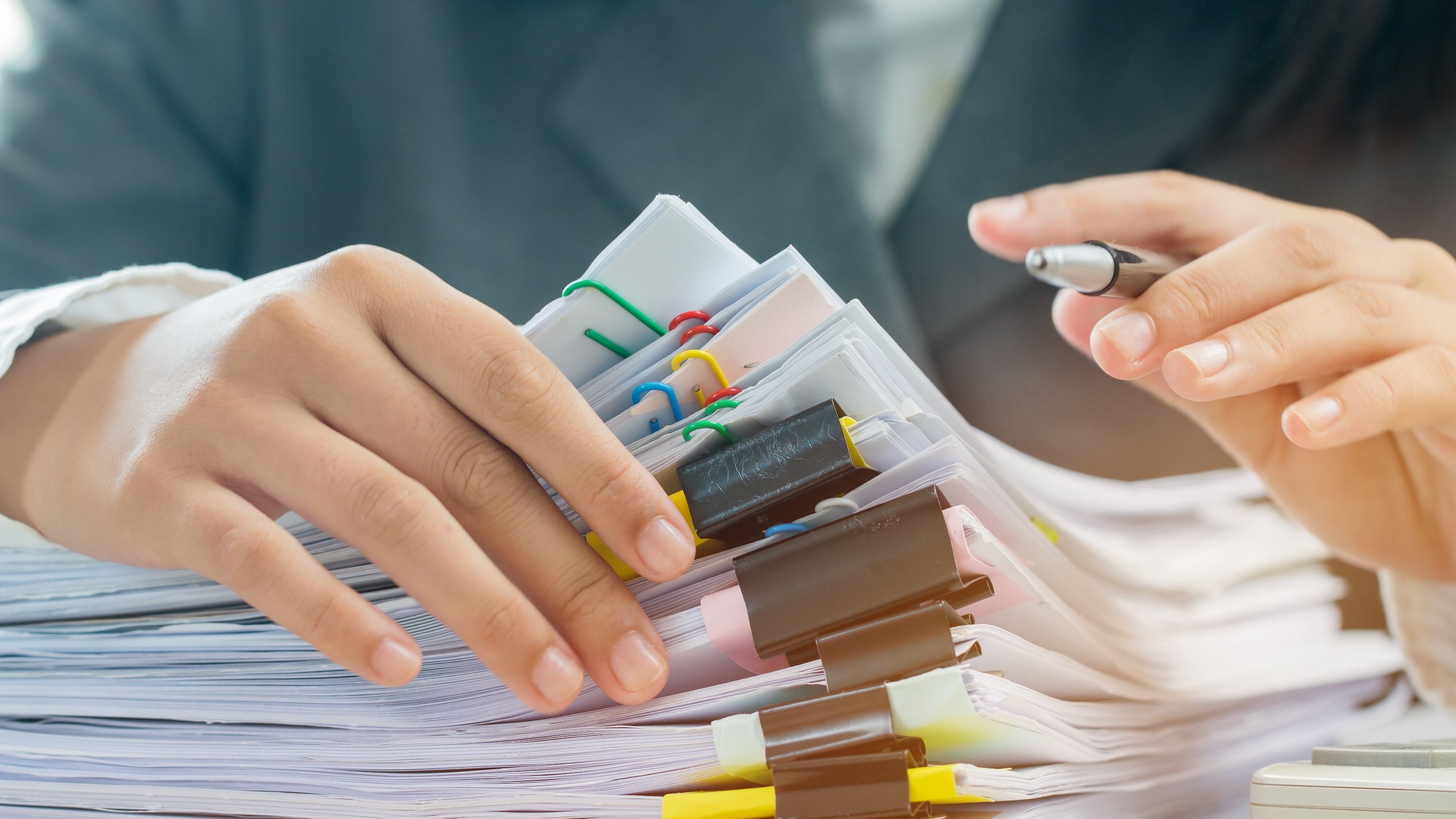 A person flips through a large pile of tax documents.