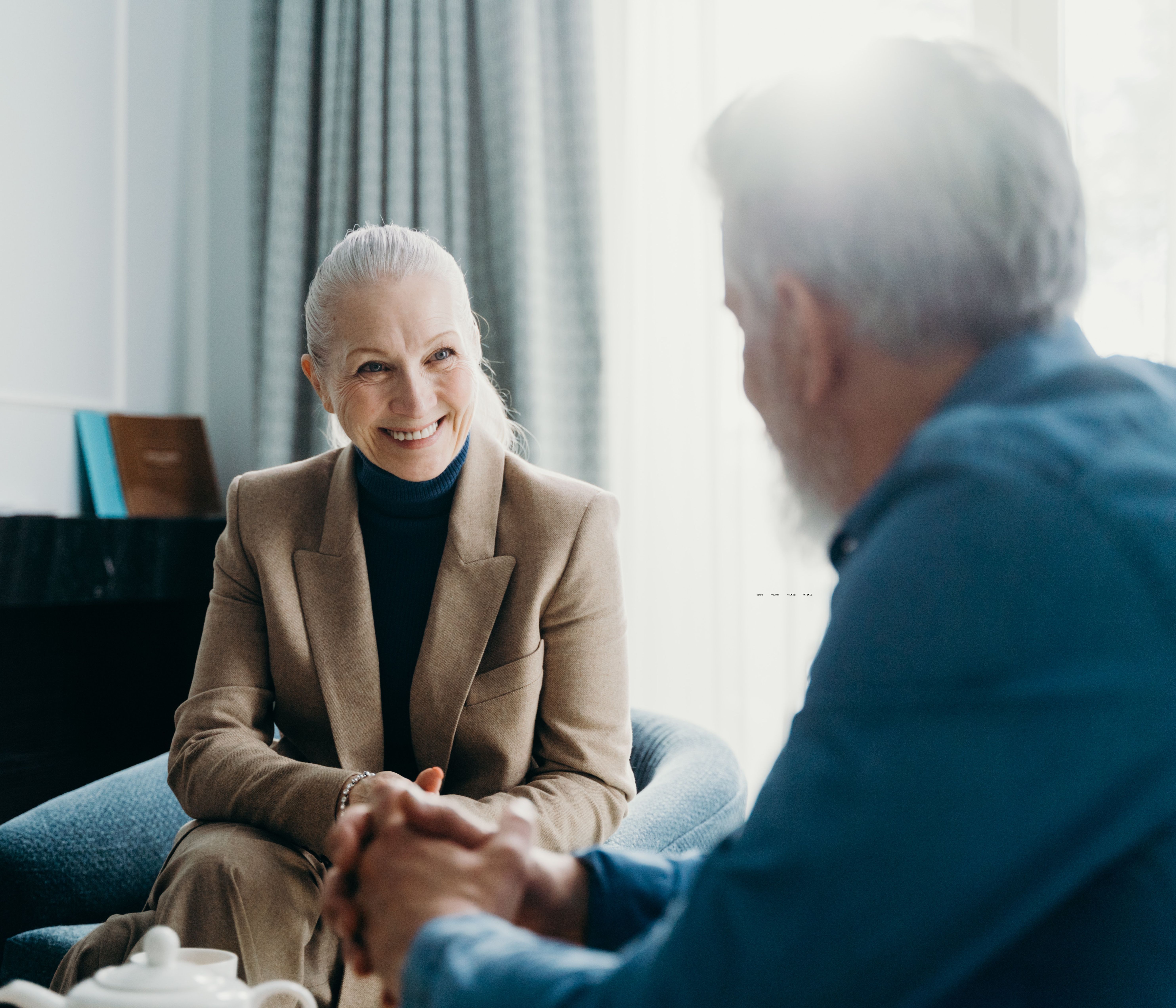 Two professionals meet with each other in small blue chairs, laughing as they chat.