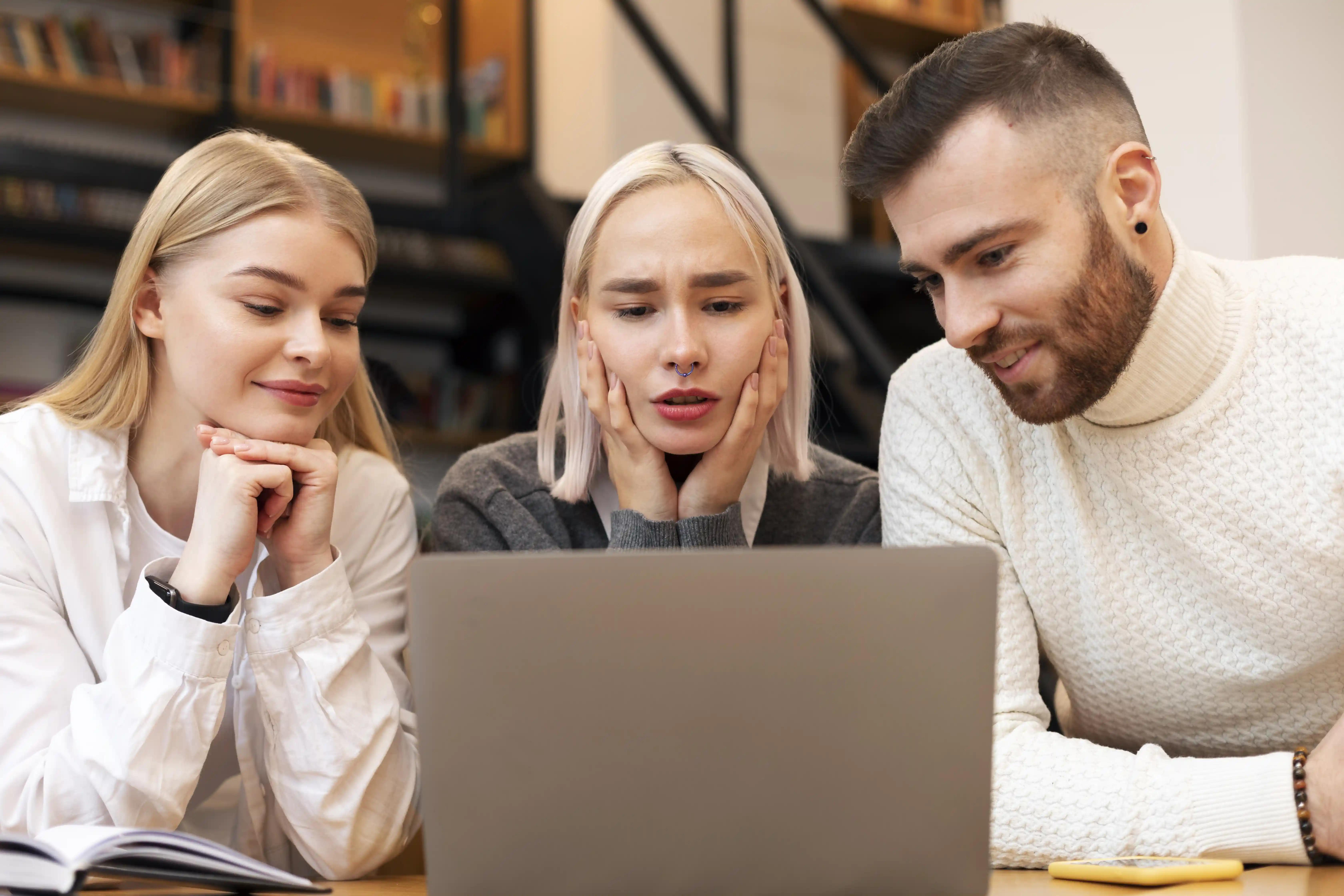 tři lidé sedí nad laptopem, aby dokončili zadání webařce