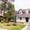 A cute two story office with porch on right with lamppost in front and a gazebo on left with pine trees in the background