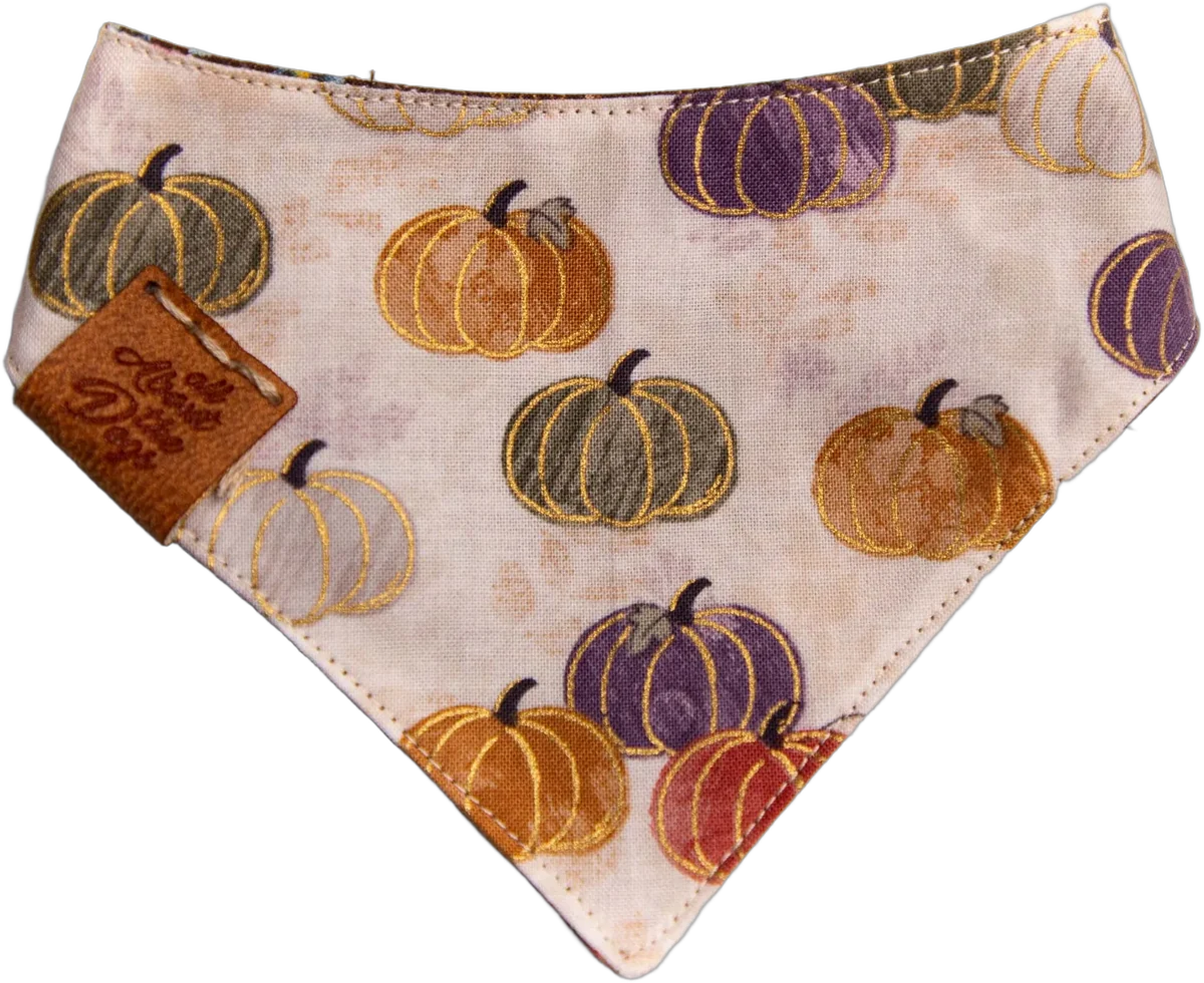 A reversible dog bandana in a cream print with orange, purple and sage pumpkins