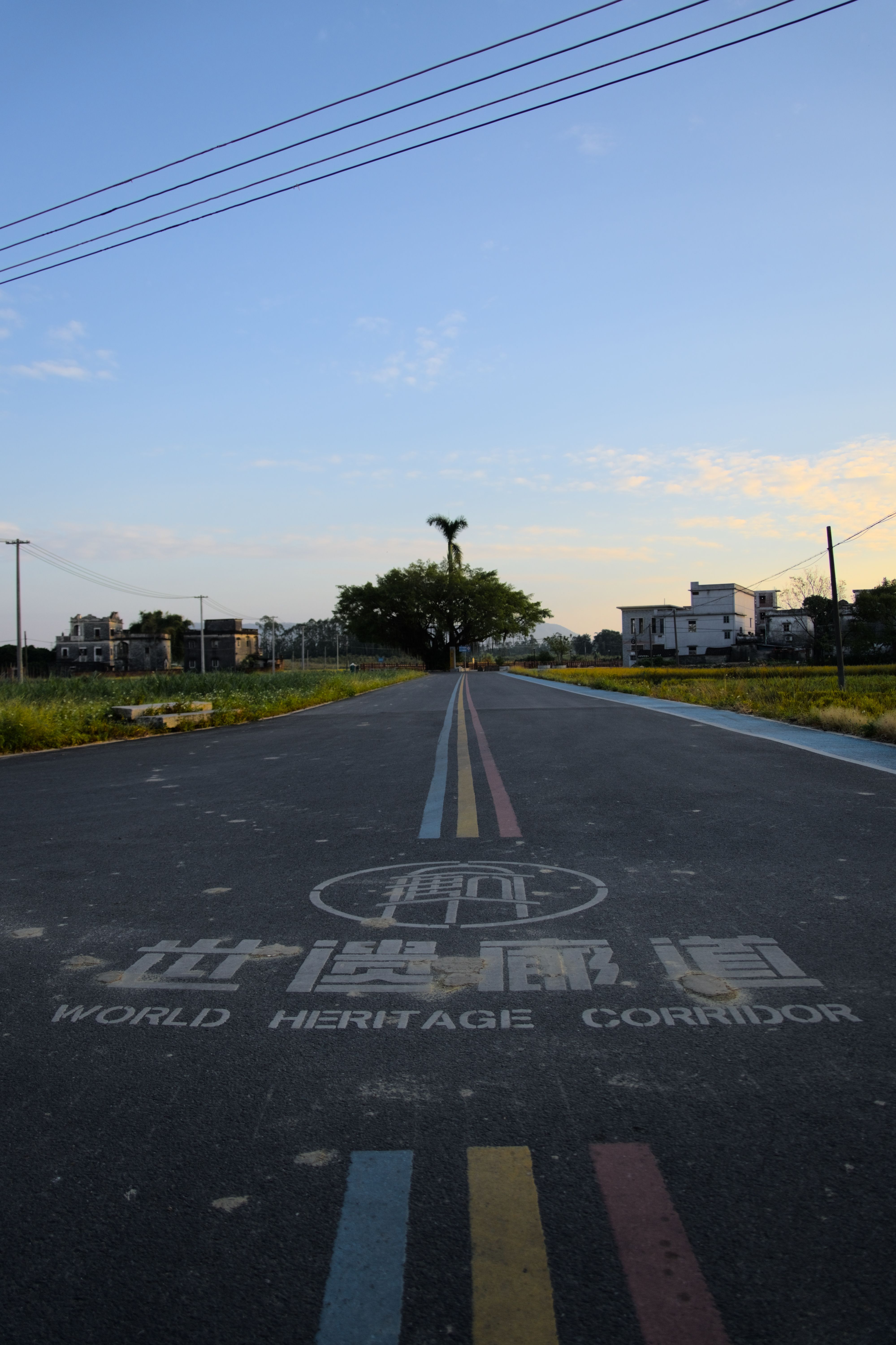 A road with blue, yellow, and red stripes down the center with the words "World Heritage Corridor" in English and Chinese. 