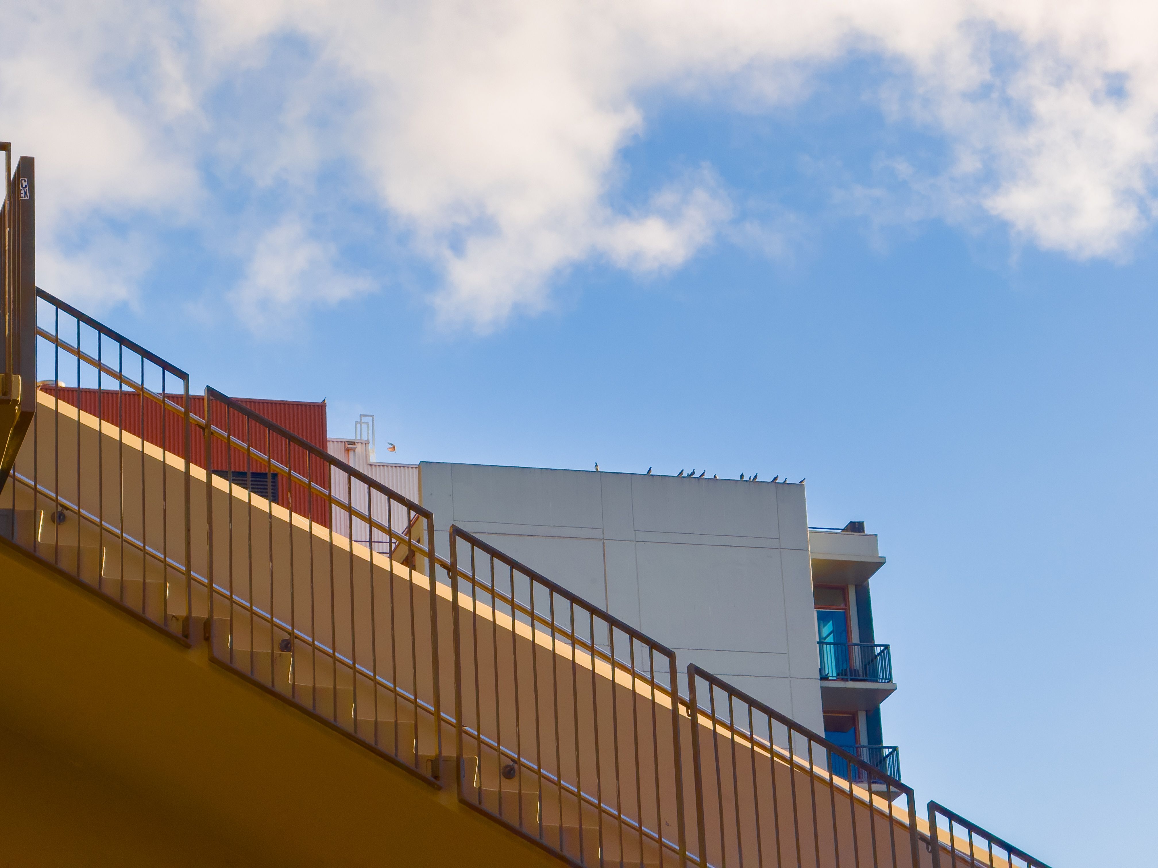 A red building and a light blue building with a yellow staircase cutting sideways in front of them