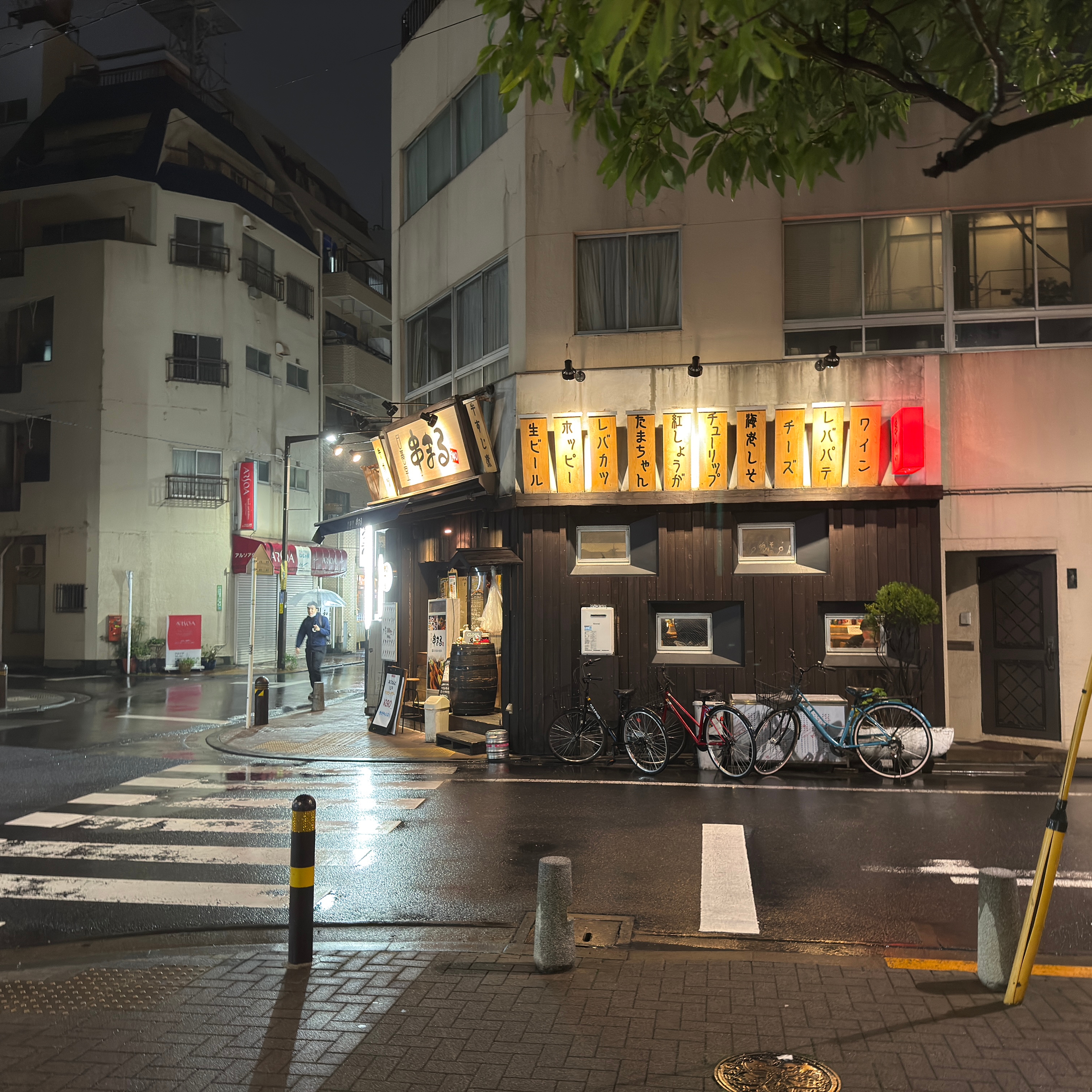 A restaurant on a rainy night with three bicycles parked outside.