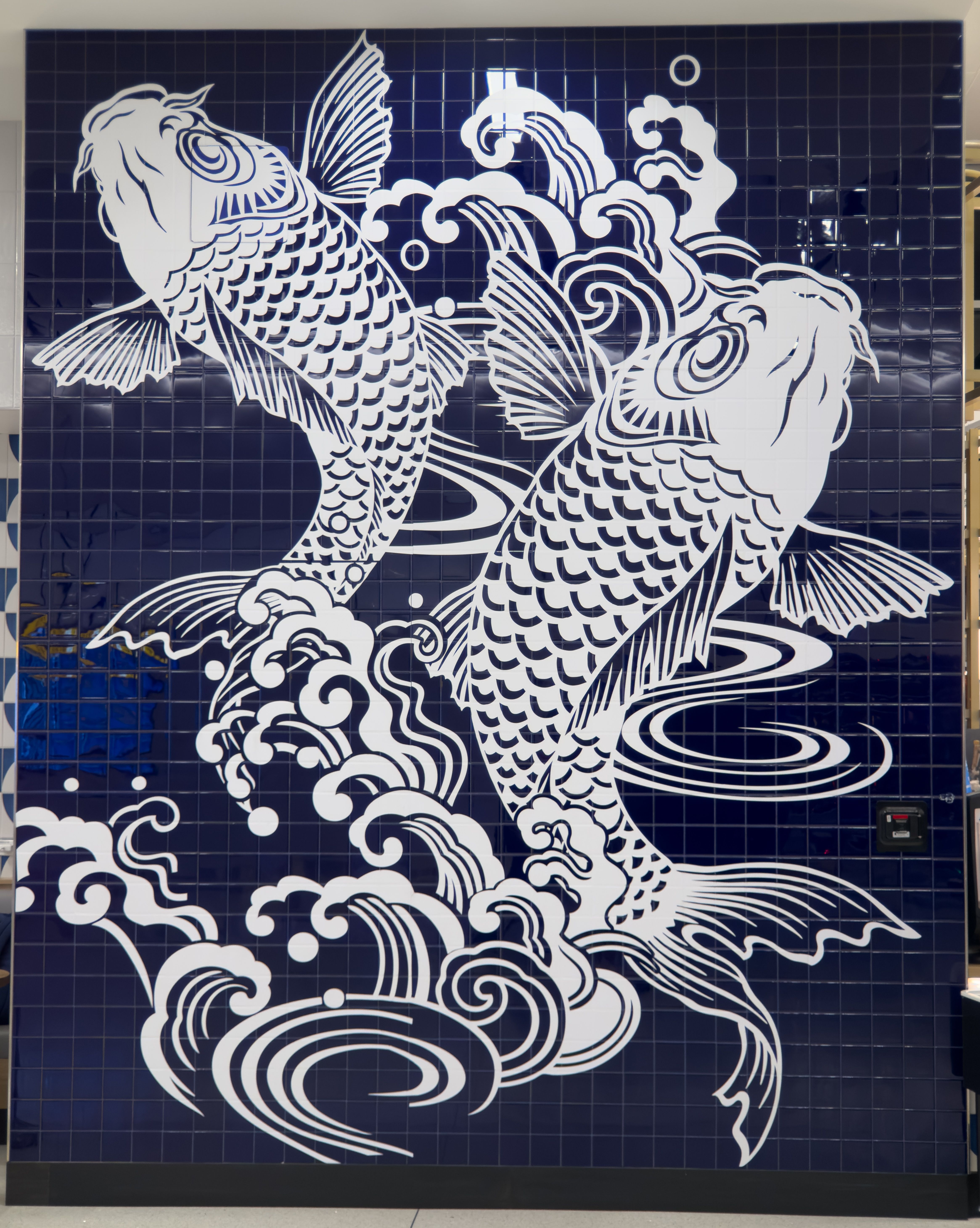 Two white koi fish painted on dark blue tile