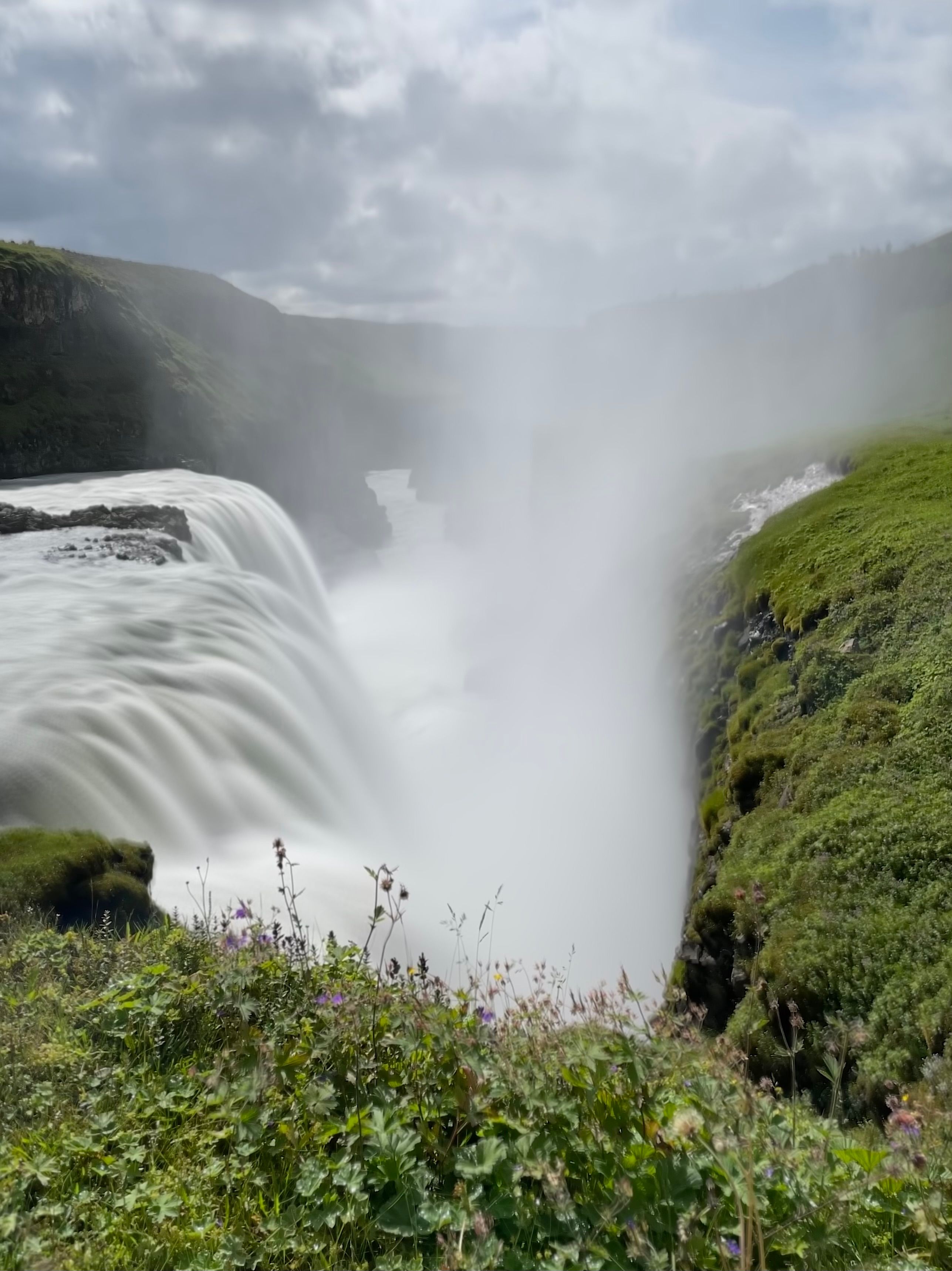A lush waterfall with mist rising off it