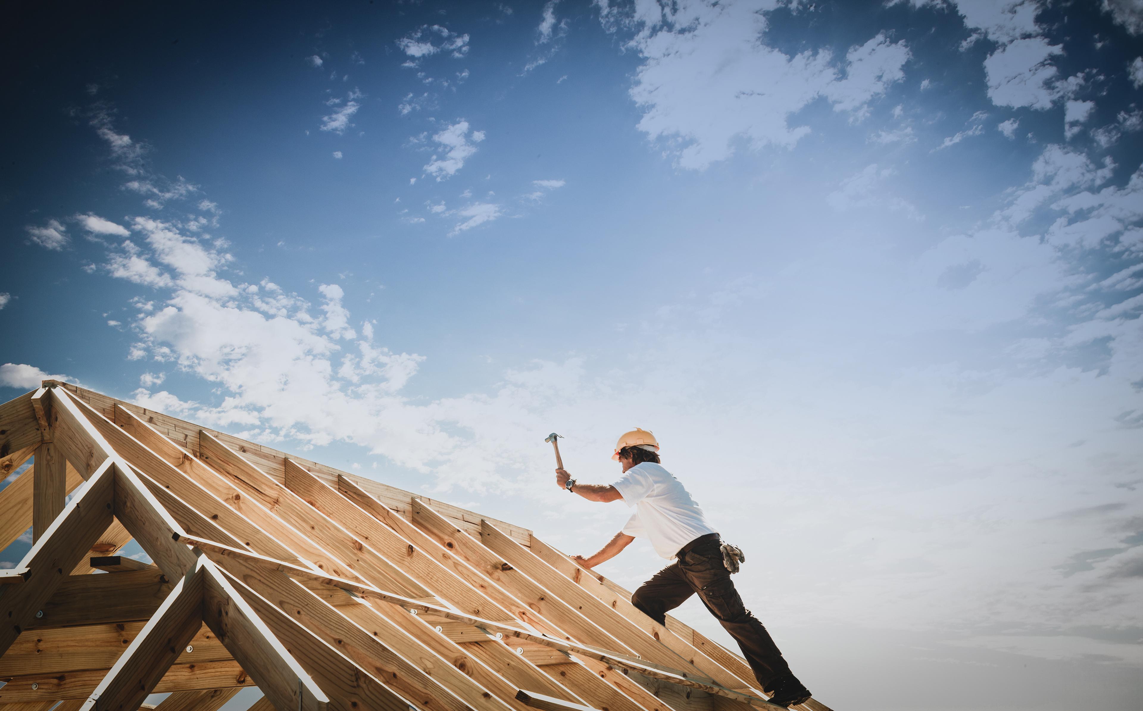 Man holding hammer, climbing on a roof