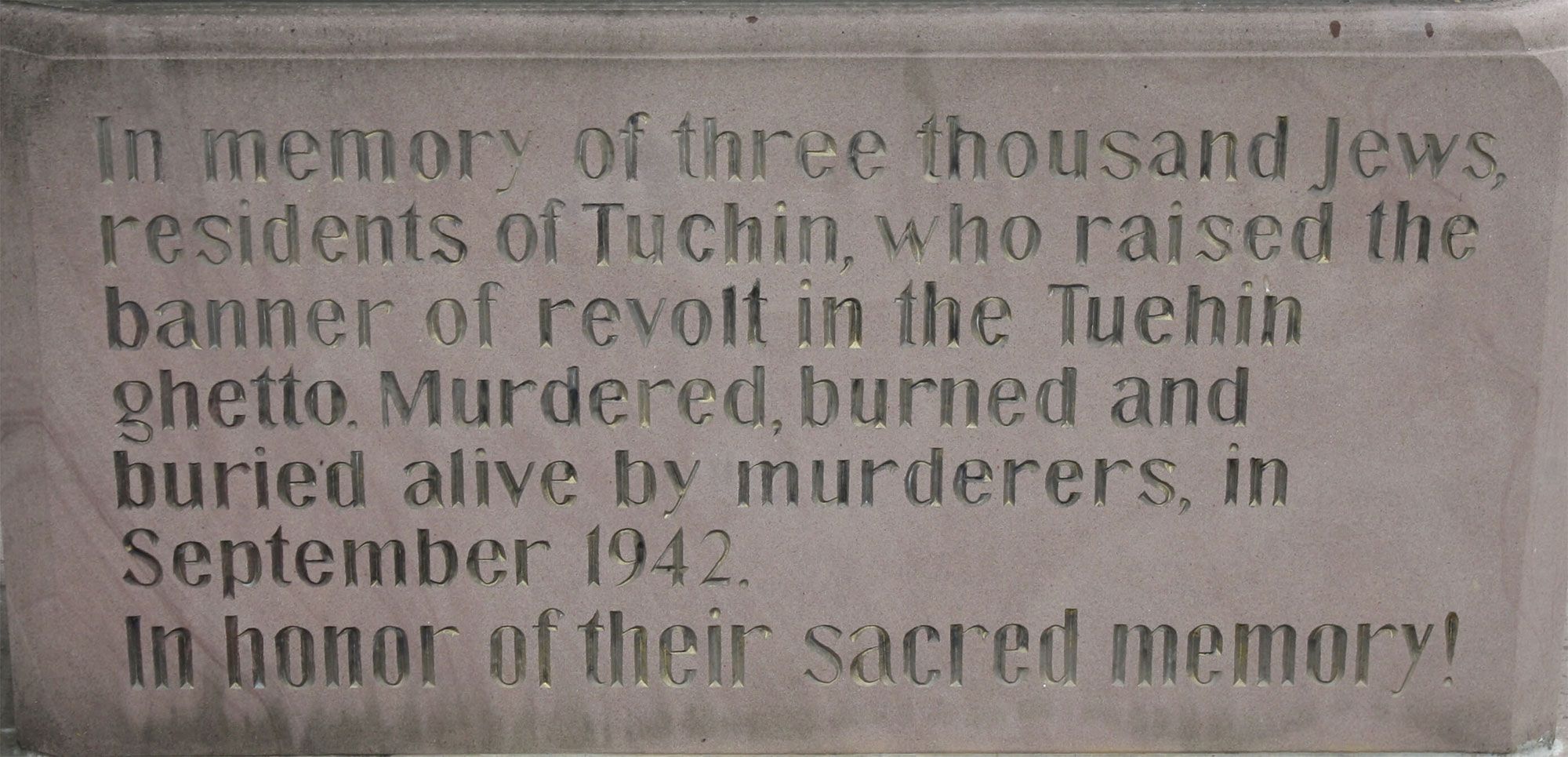 Close up of the text of the monument. Text reads: In memory of three thousand Jews, residents of Tuchin, who raised the banner of revolt in the Tuchin ghetto. Murdered, burned, and buried alive by murderers, in September 1942. In honor of their sacred memory!