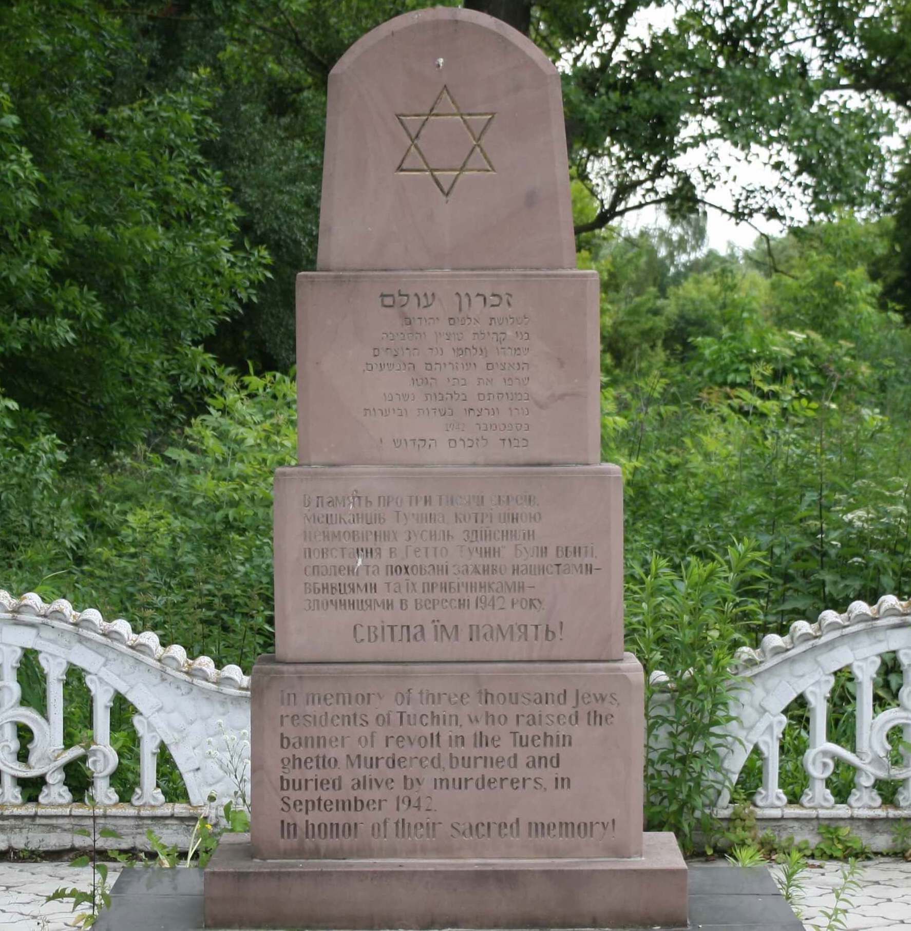 Photograph of a four-tiered stone monument with Ukrainian text on the lower tiers and a Star of David on the top tier.