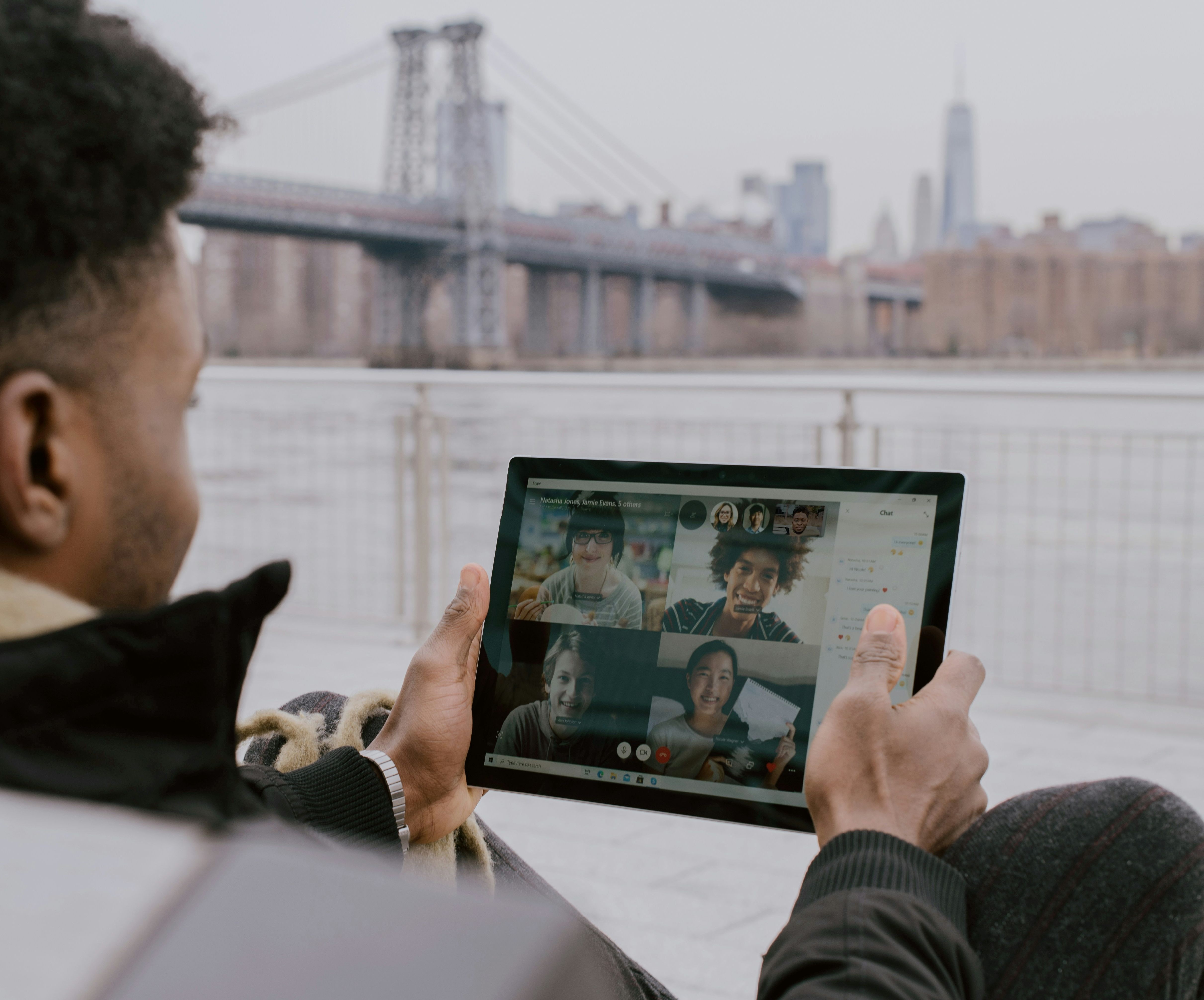 A person on a video call on a tablet, with a city skyline behind them