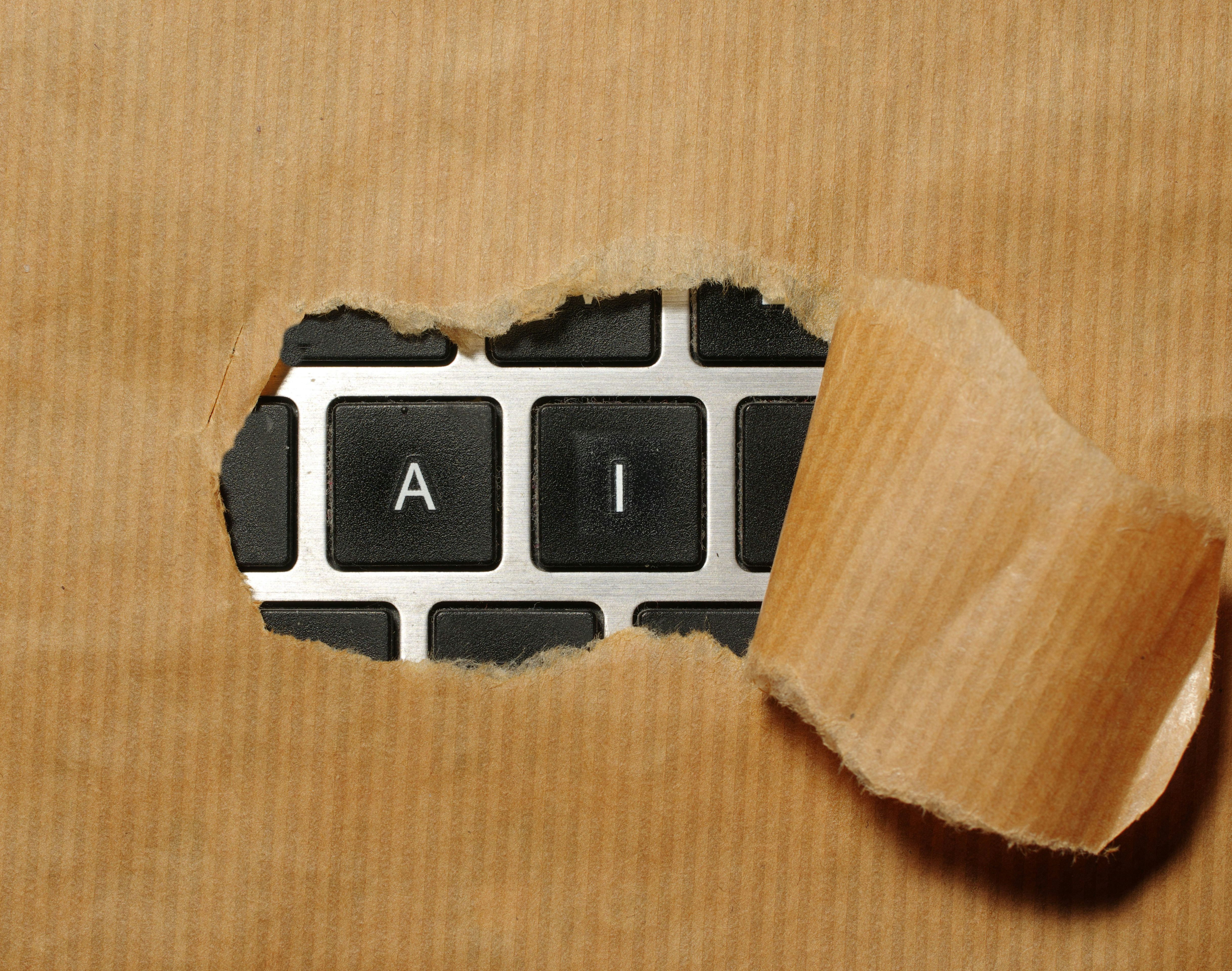Torn brown paper revealing computer keyboard keys that spell the letters A and I