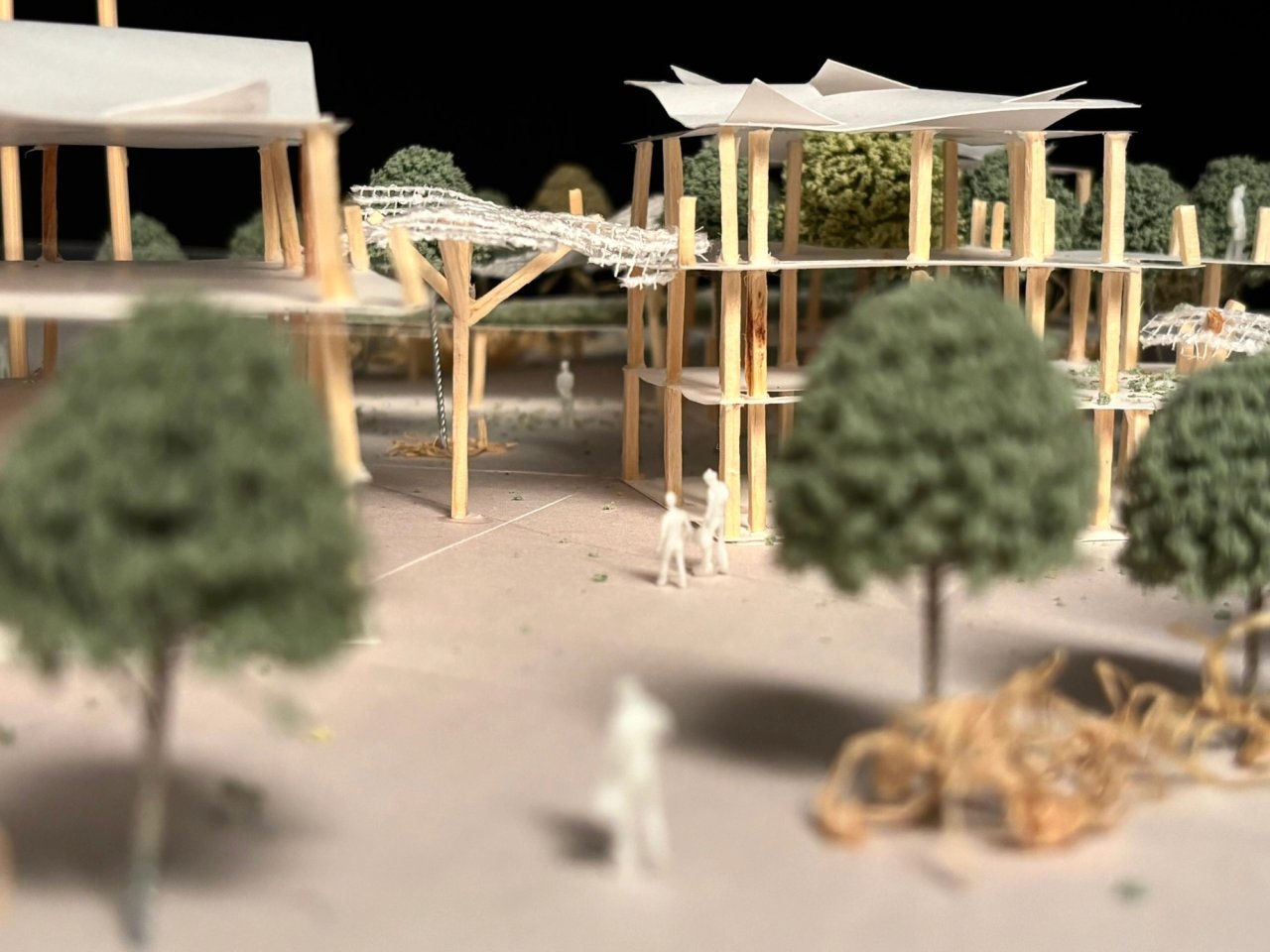 Eye-level photograph of the site model, looking between timber columns towards a canopy and a raised walkway.