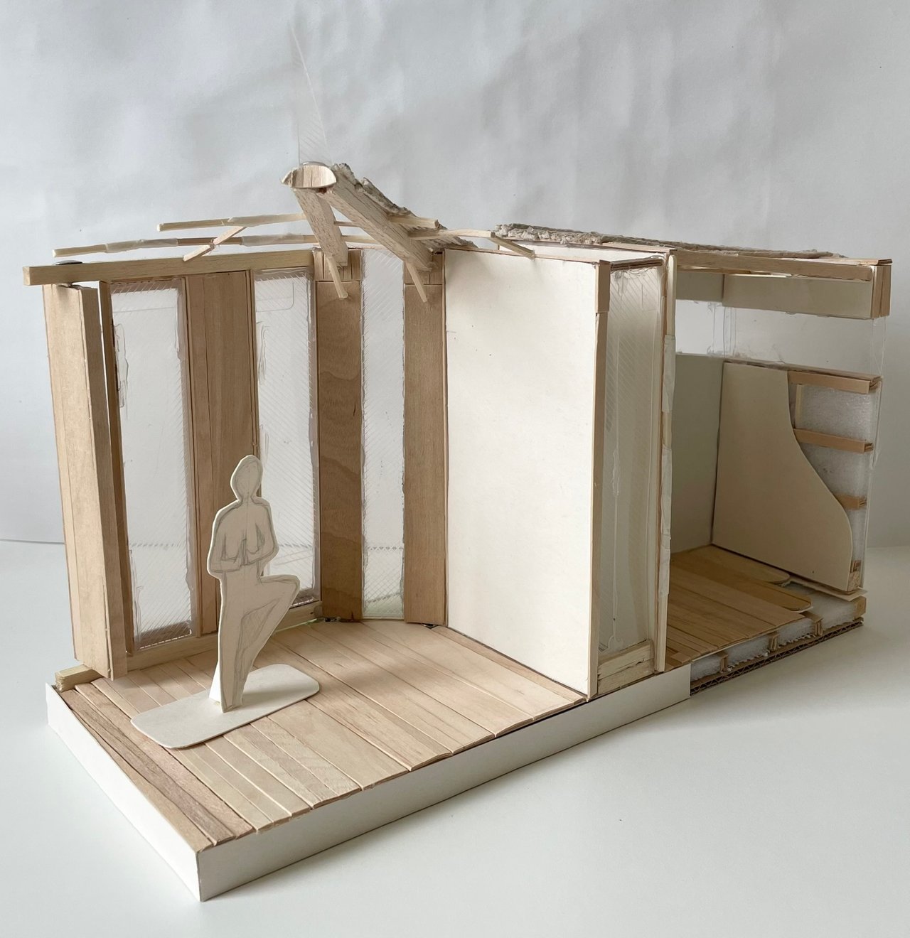 Larger model of the pavilion, with a plank floor, sliding screens and a paper figure standing in tree pose.
