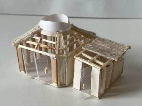 Small timber-frame model of the pavilion, with a thatched roof and a white dome over the central space.