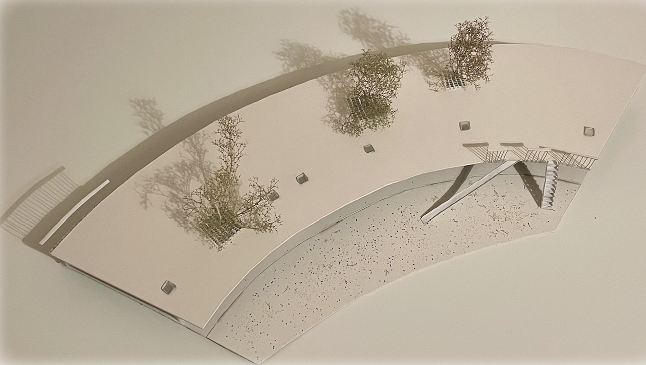 Aerial photograph of the card model of a roof segment, with model trees pushing through it and a slide down to the courtyard.