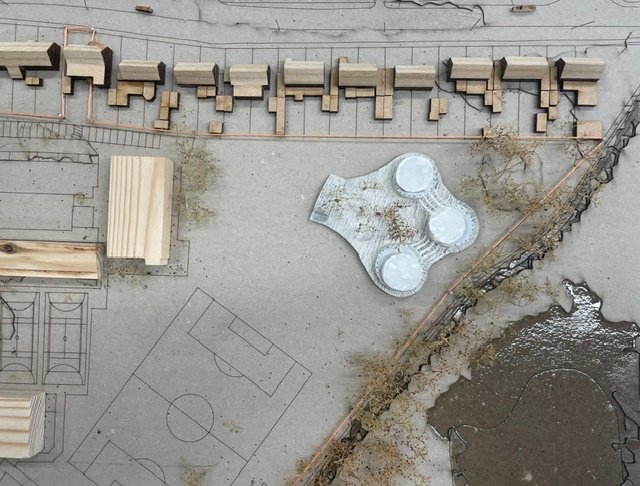 Aerial photograph of the site model: the circular blocks sit among terraced houses, playing fields and the river.