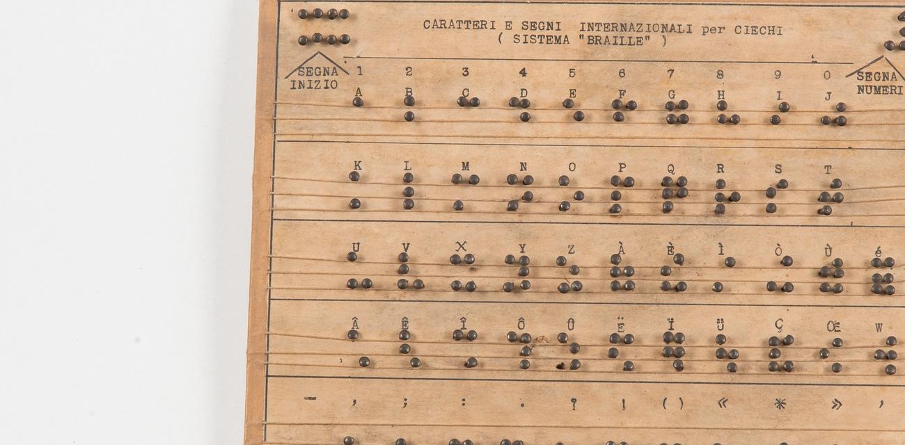 Tavoletta in legno che illustra la punteggiatura del sistema braille
