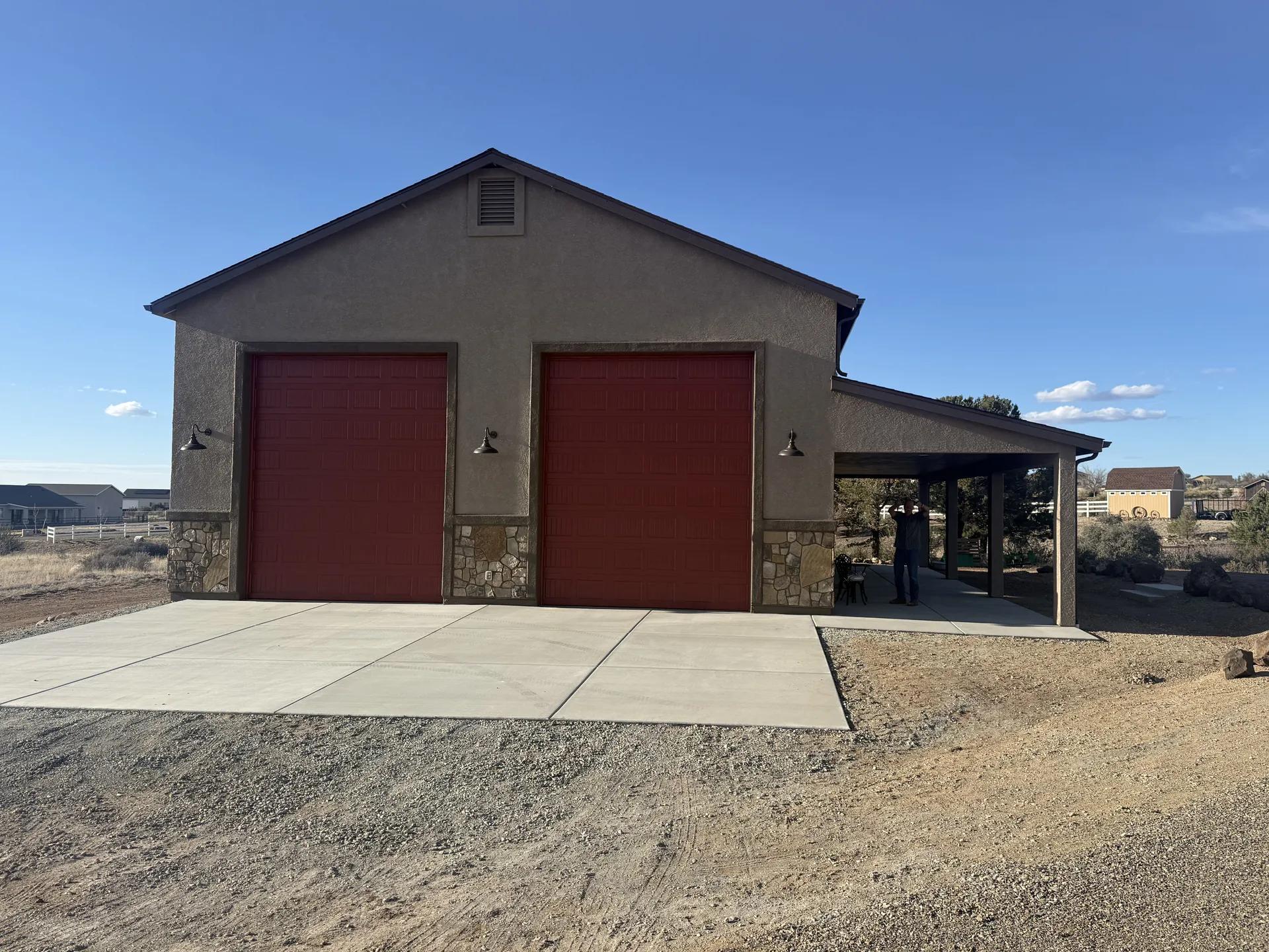 Completed Legend Hills RV garage with two tall red doors and a covered side work area