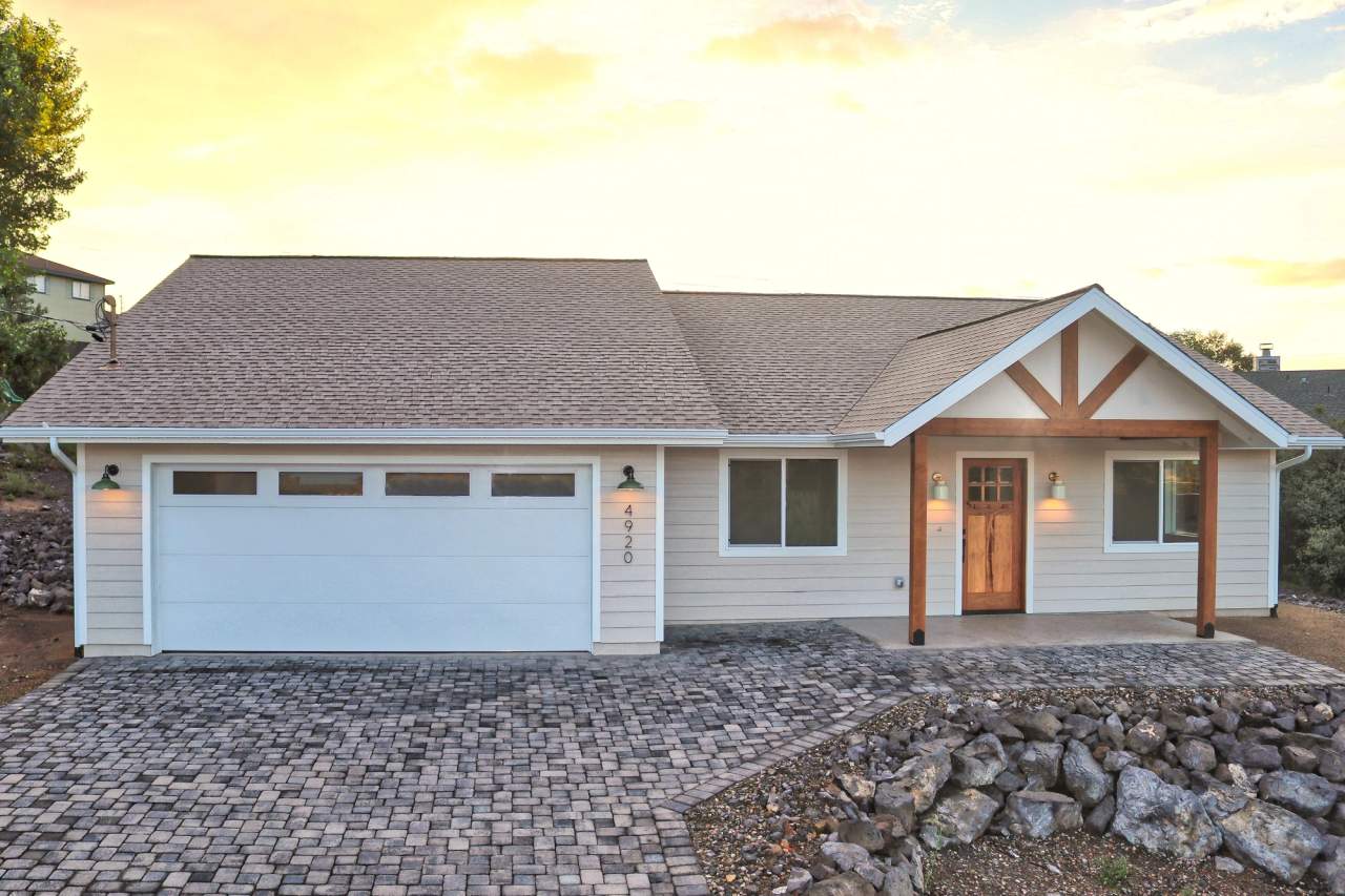 Completed single-story spec home with an attached garage and timber-framed entry