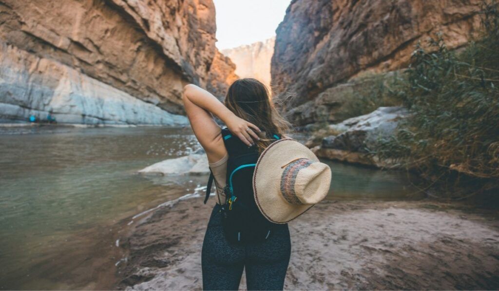 A hiker with a straw hat gazes into the limestone canyon walls of Santa Elena Canyon at Big Bend Ranch State Park